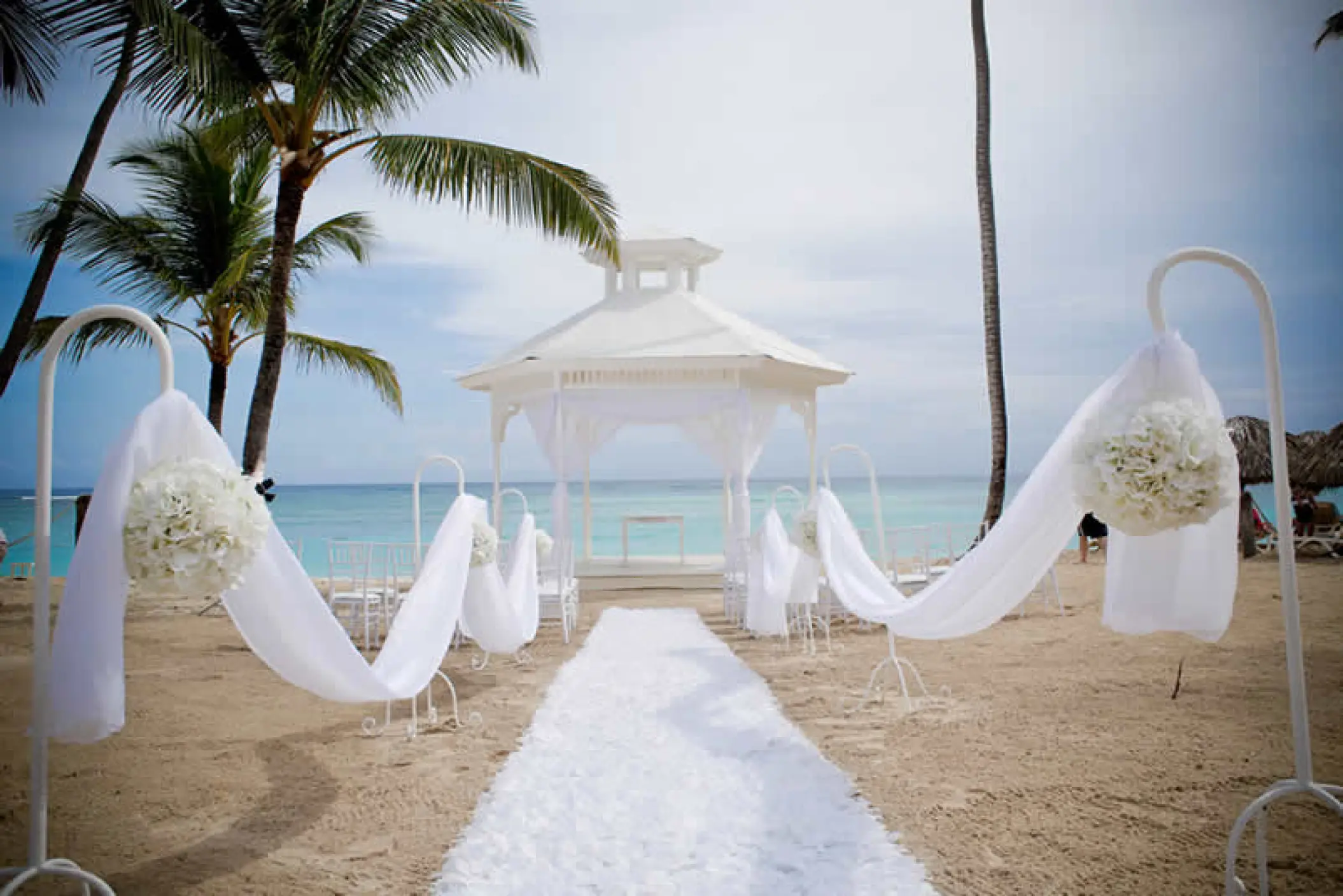 Beachfront wedding ceremony gazebo with white drapery and aisle runner at Majestic Elegance, Punta Cana