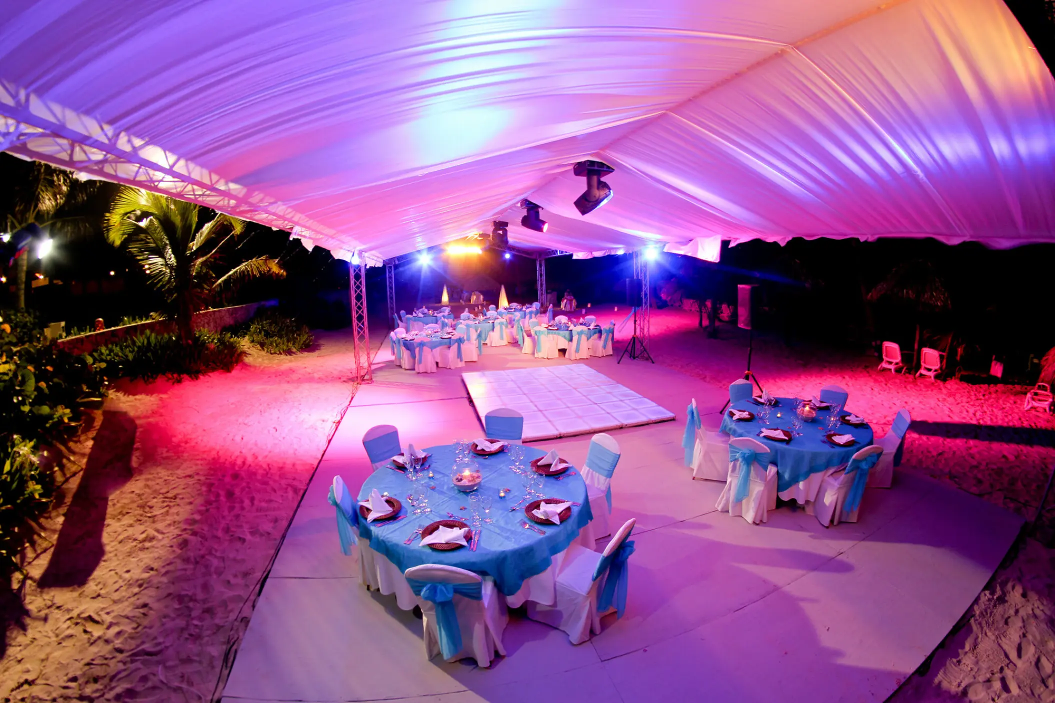 Beachfront wedding reception under a marquee with pink lighting at Majestic Elegance Punta Cana