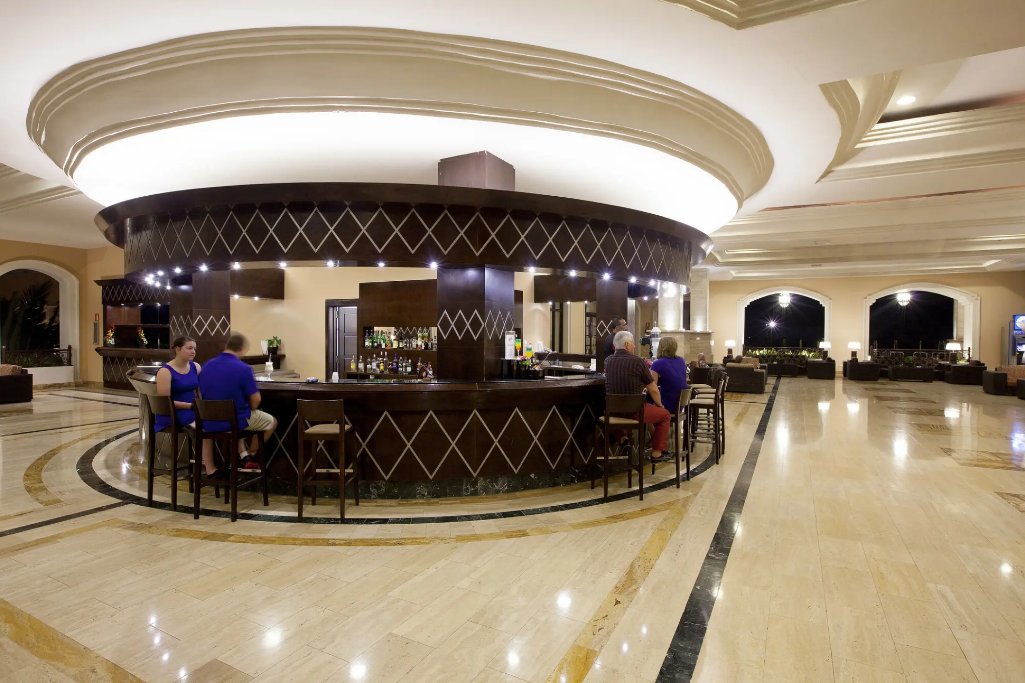 Circular piano bar with guests sitting on stools at Majestic Elegance Punta Cana