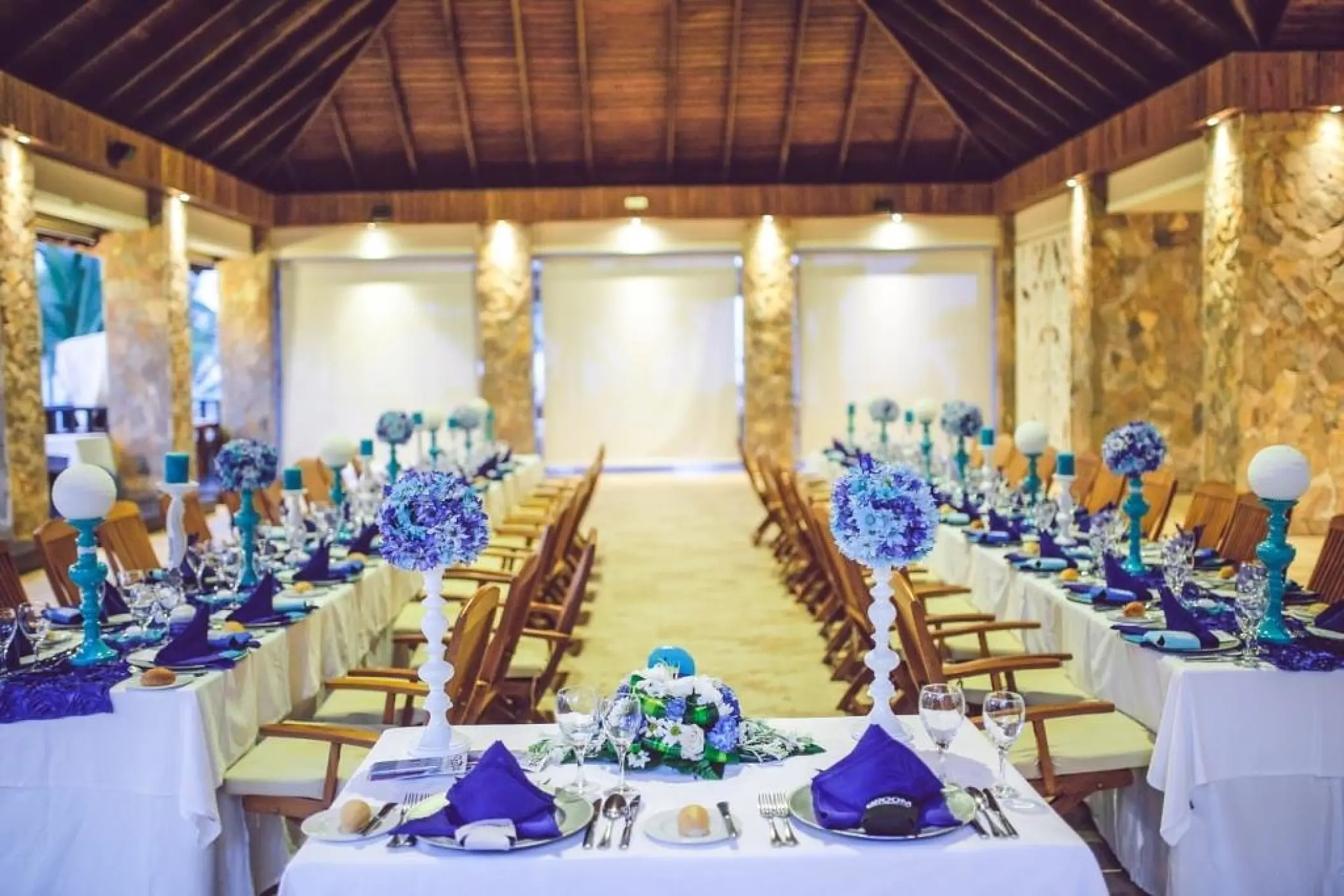 Indoor wedding reception with blue floral centerpieces and purple linens at Majestic Elegance, Punta Cana