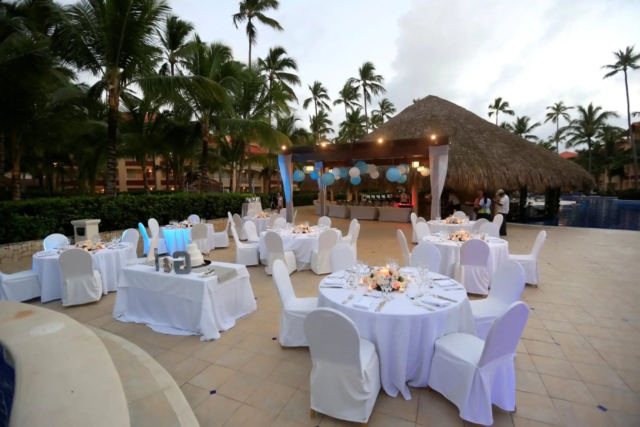 Outdoor wedding reception with white tables by the pool at Majestic Elegance, Punta Cana
