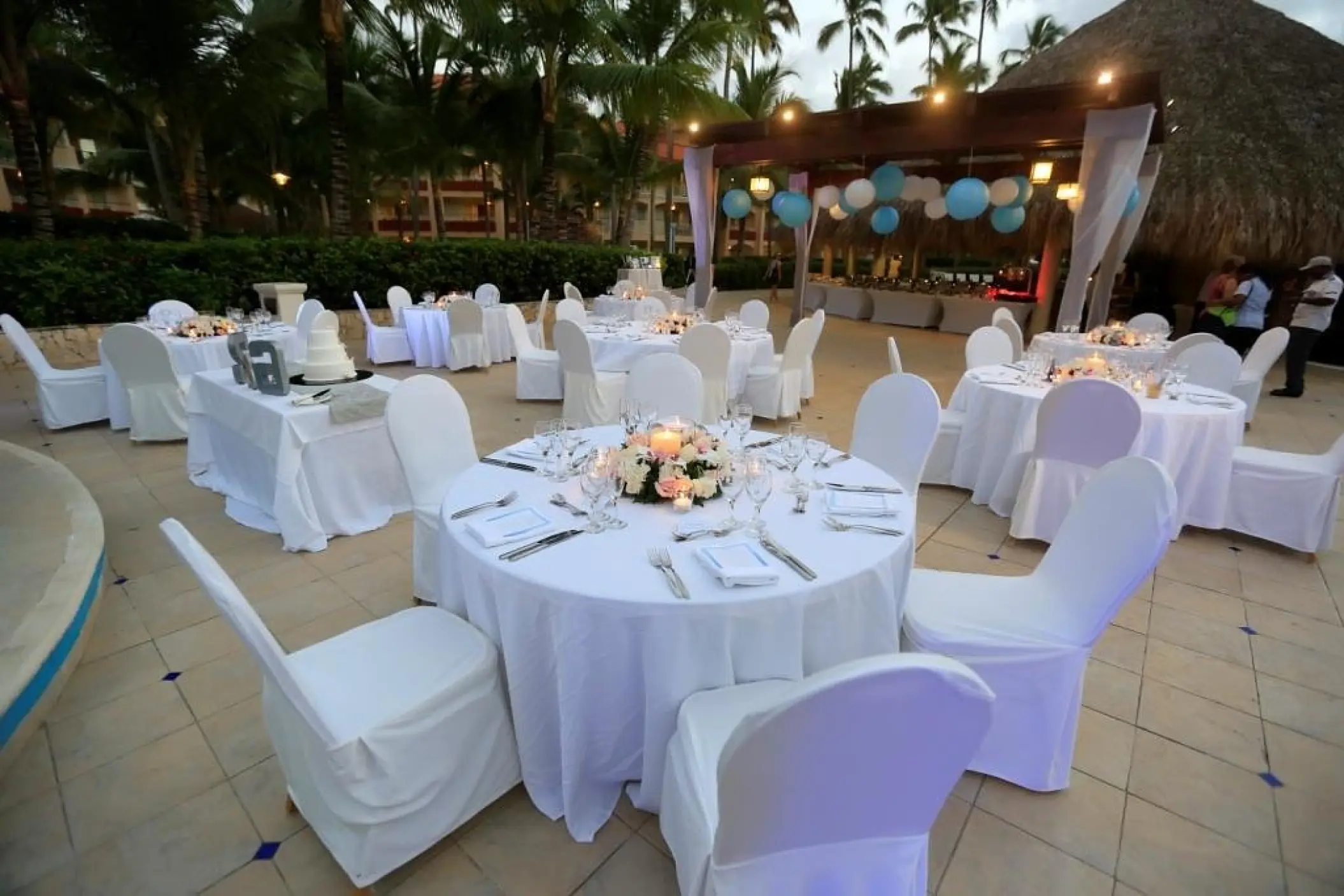 Outdoor wedding reception setup with white linens and blue lanterns at Majestic Elegance Punta Cana