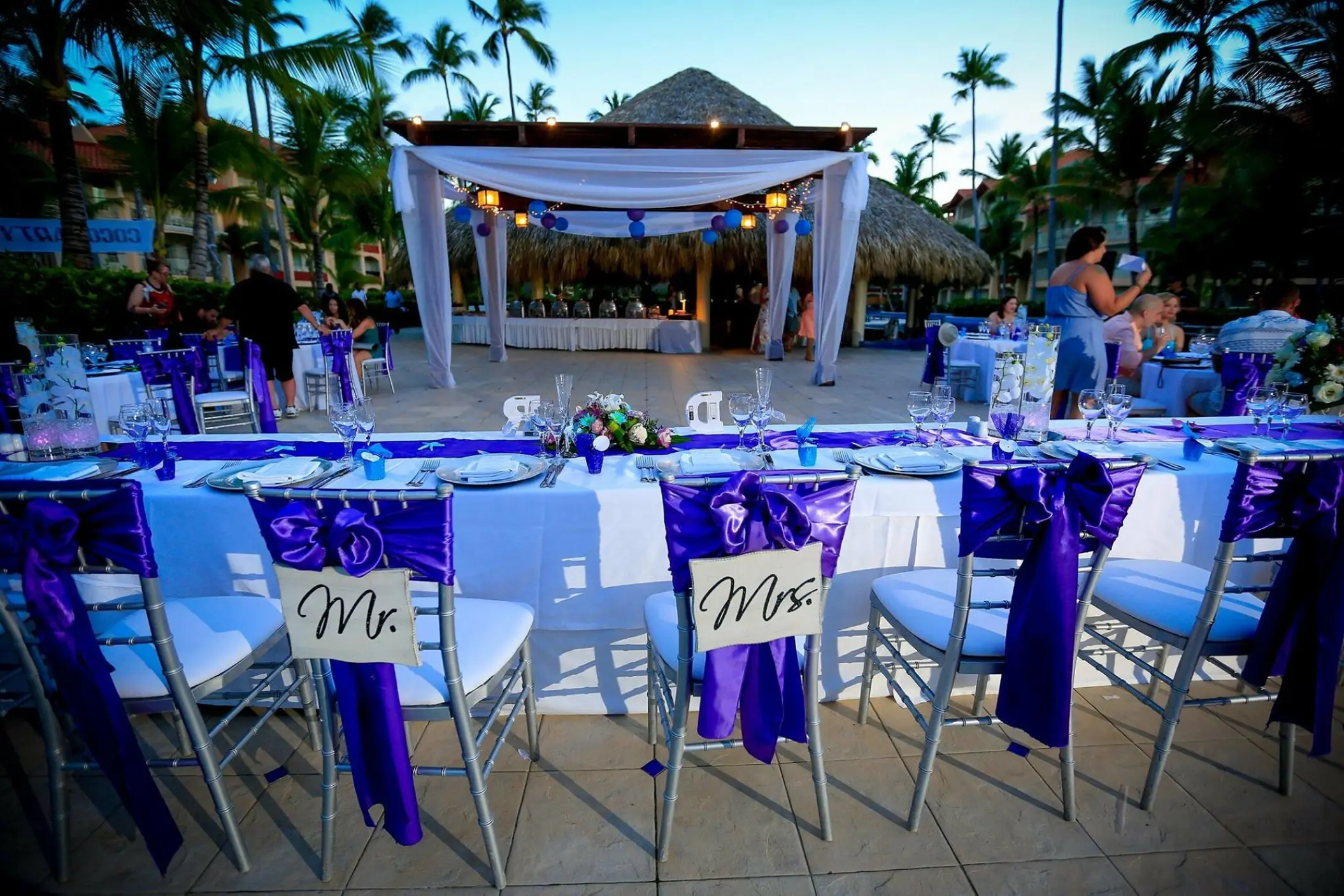 Outdoor wedding reception with purple decor and Mr. and Mrs. chair signs at Majestic Elegance, Punta Cana