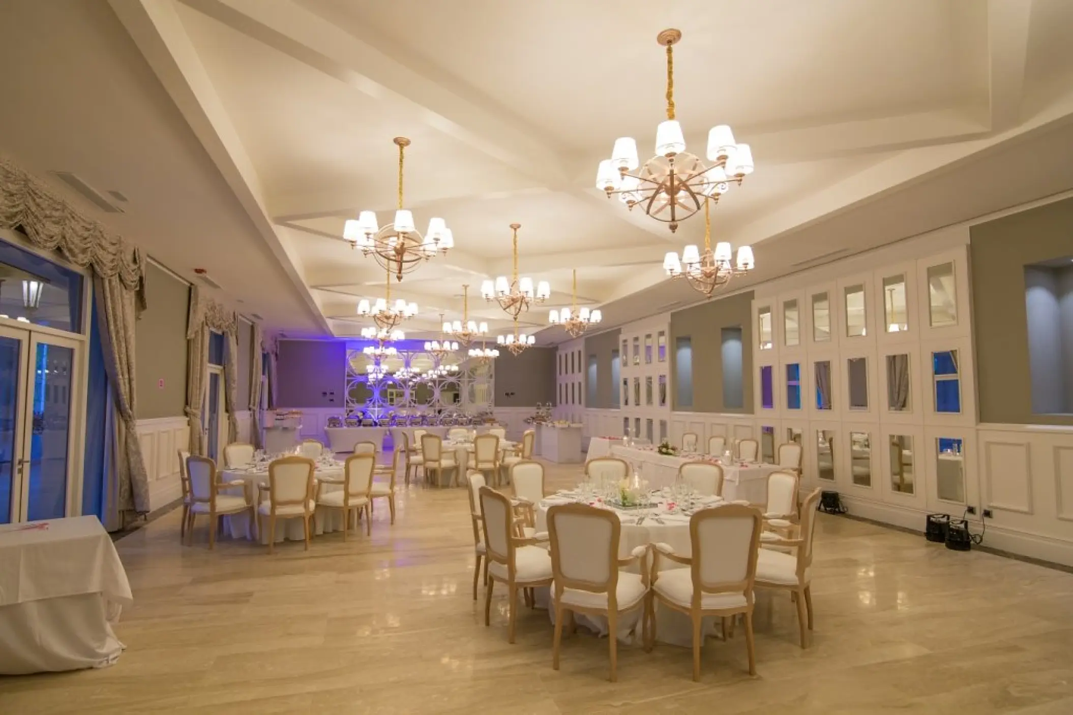 Indoor wedding reception ballroom with chandeliers and round tables at Majestic Mirage, Punta Cana