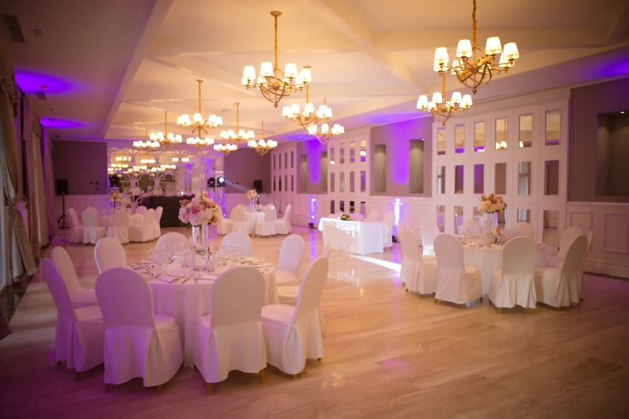Indoor wedding reception with round tables and purple uplighting at Majestic Mirage, Punta Cana