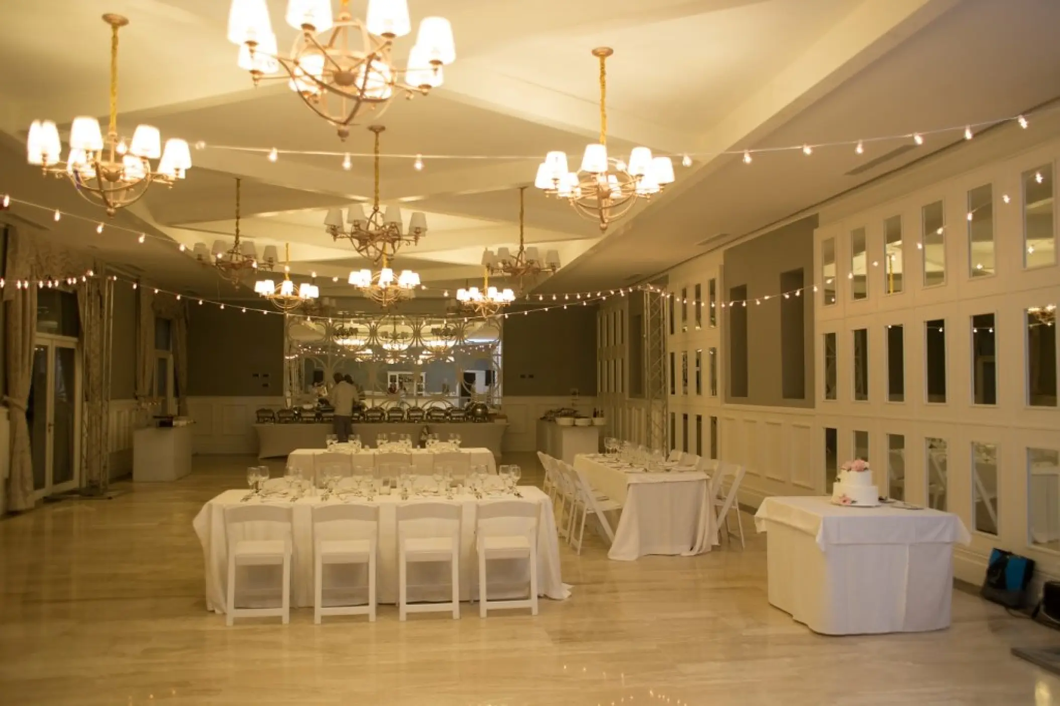 Indoor wedding reception with string lights and white table settings at Majestic Mirage, Punta Cana