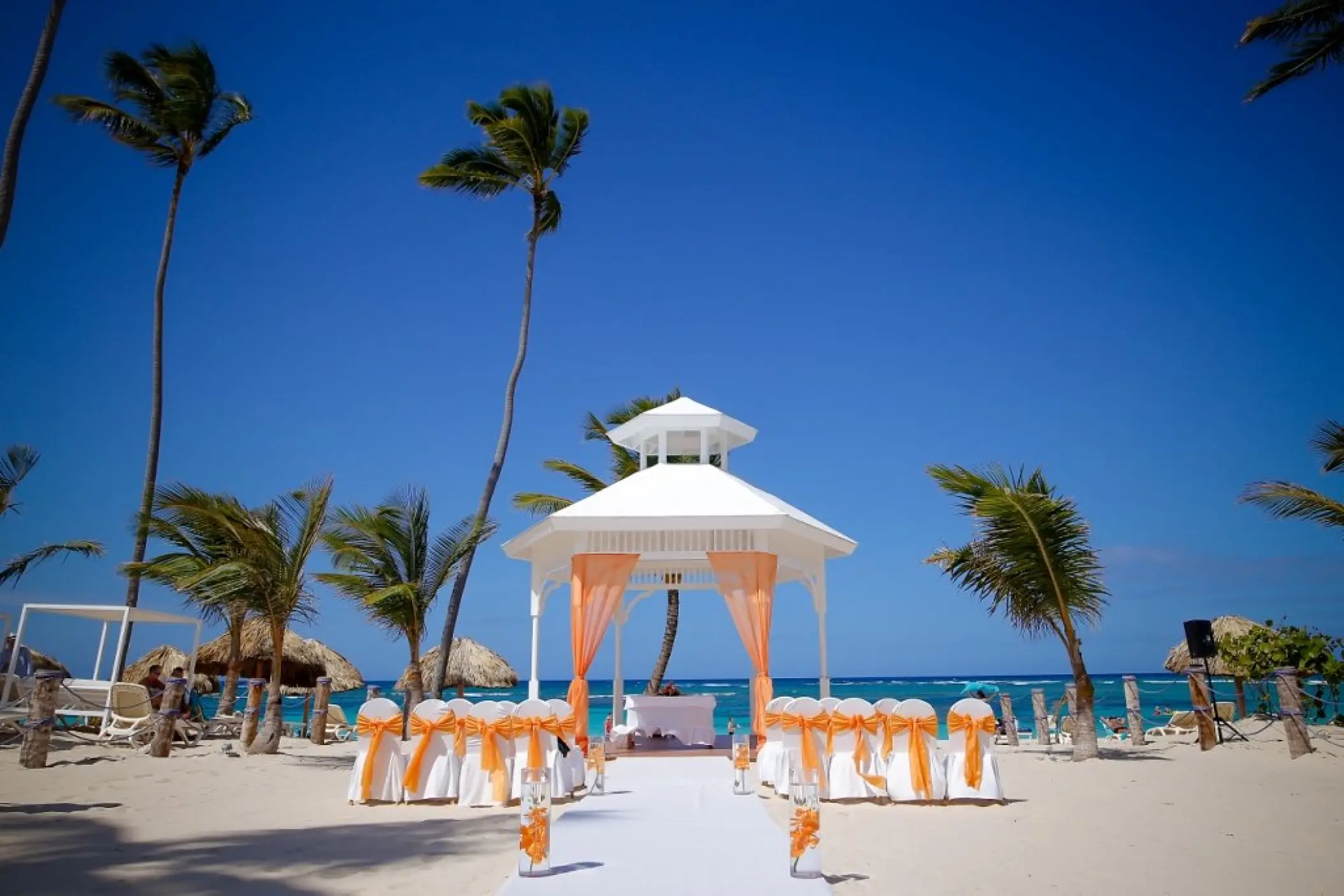 White beach gazebo wedding ceremony with orange drapes at Majestic Mirage, Punta Cana