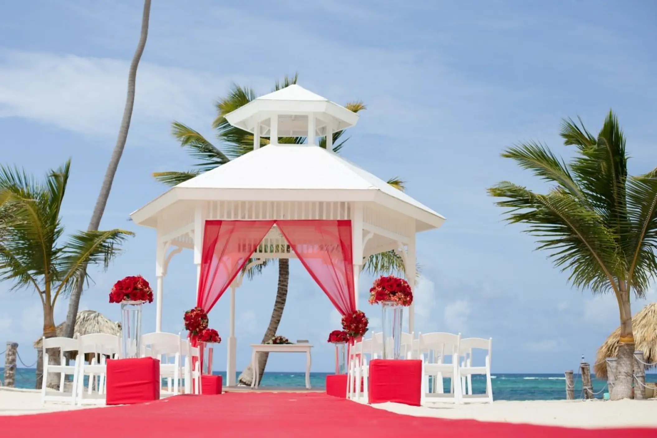 White beach wedding gazebo with red fabric and floral arrangements at Majestic Mirage, Punta Cana