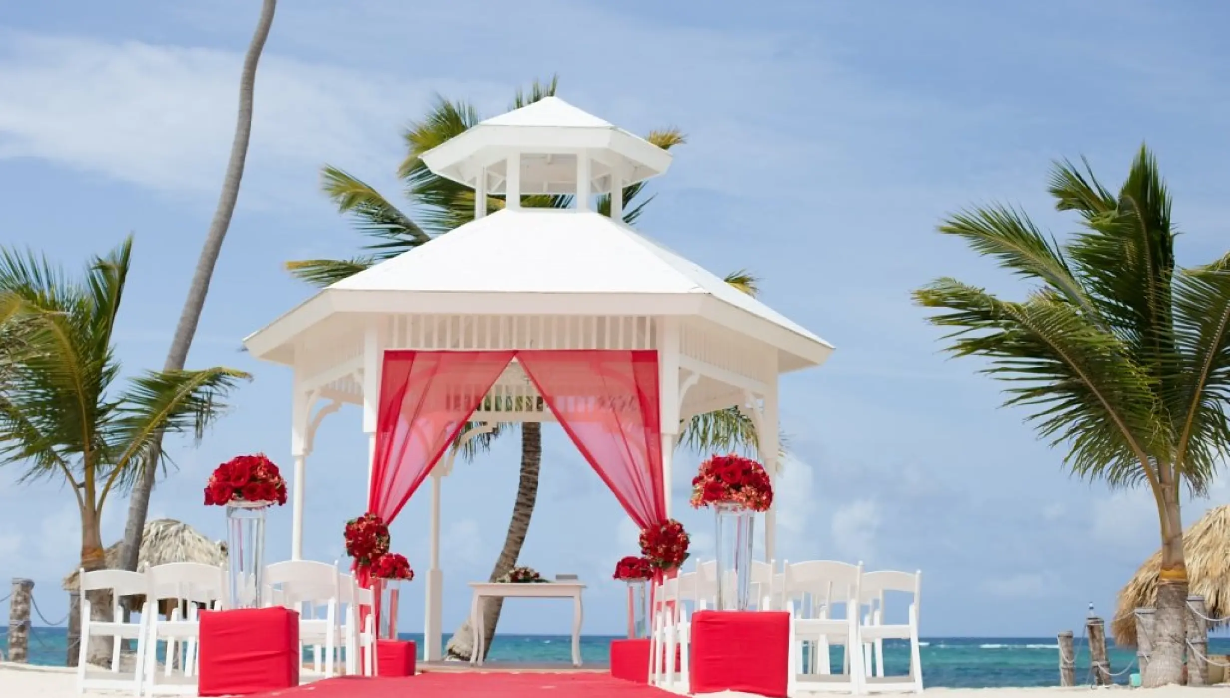 White beach wedding gazebo with red fabric and floral arrangements at Majestic Mirage, Punta Cana