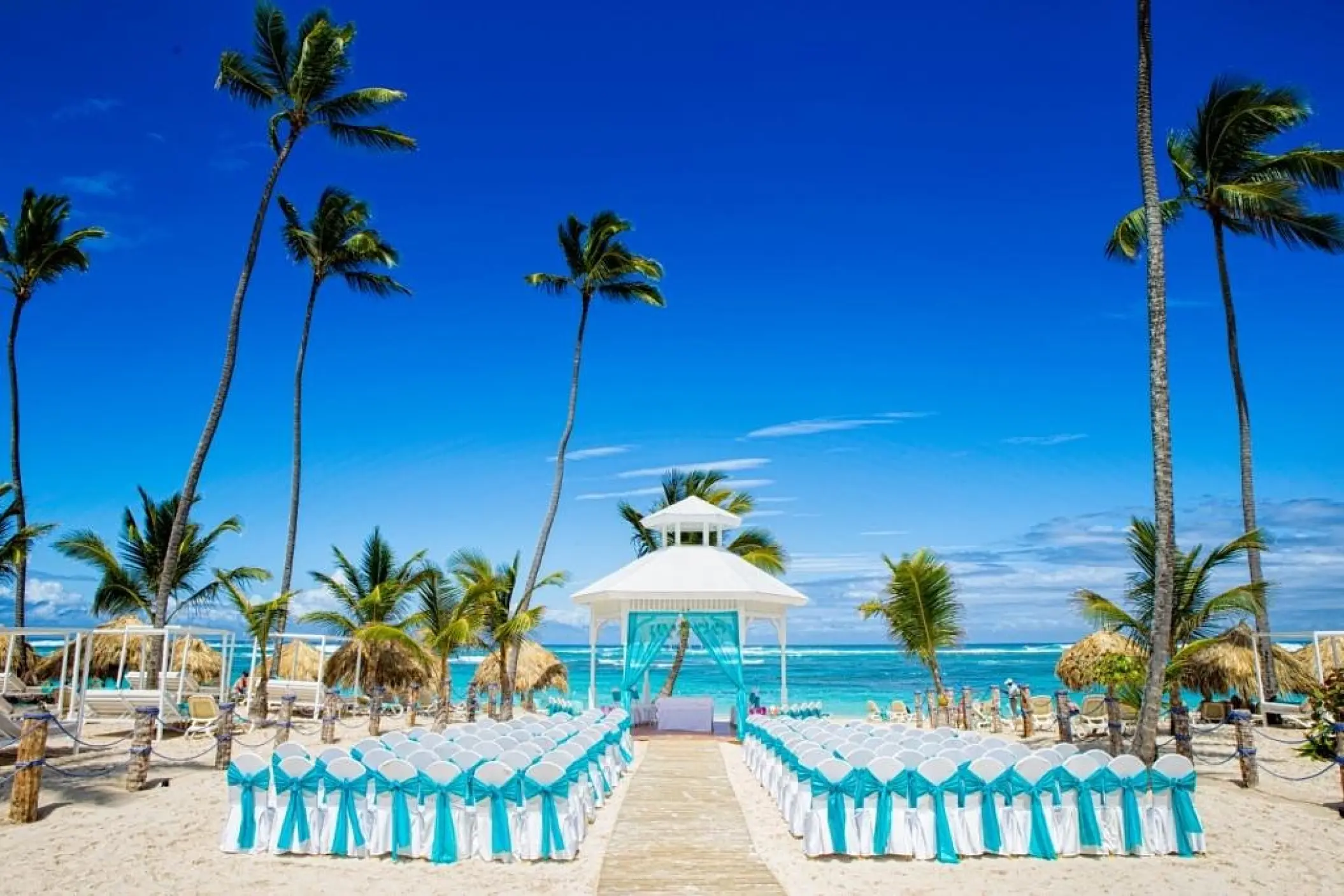 Beachfront wedding ceremony with a white gazebo and teal décor at Majestic Mirage, Punta Cana