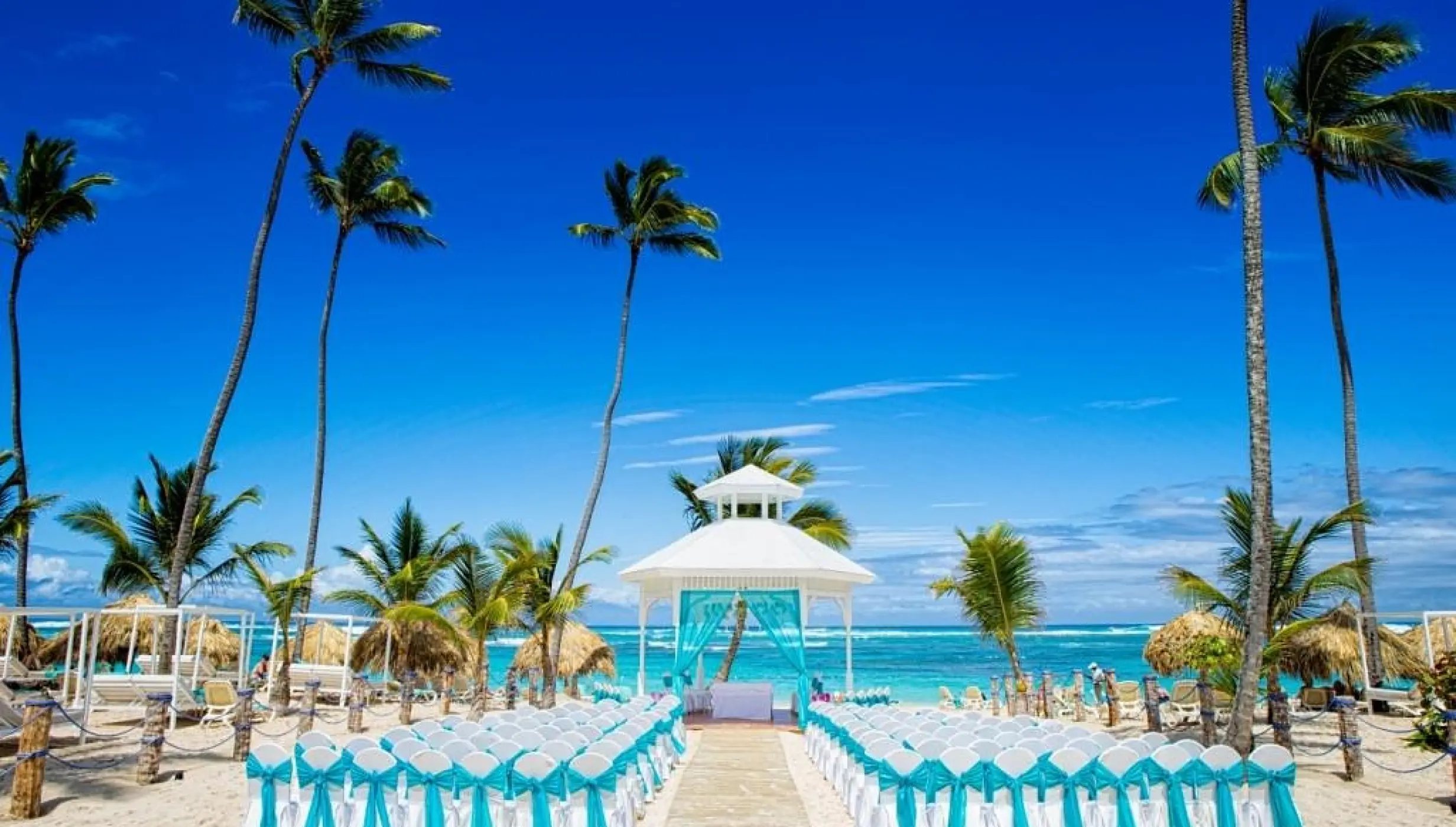 Beachfront wedding ceremony with a white gazebo and teal décor at Majestic Mirage, Punta Cana