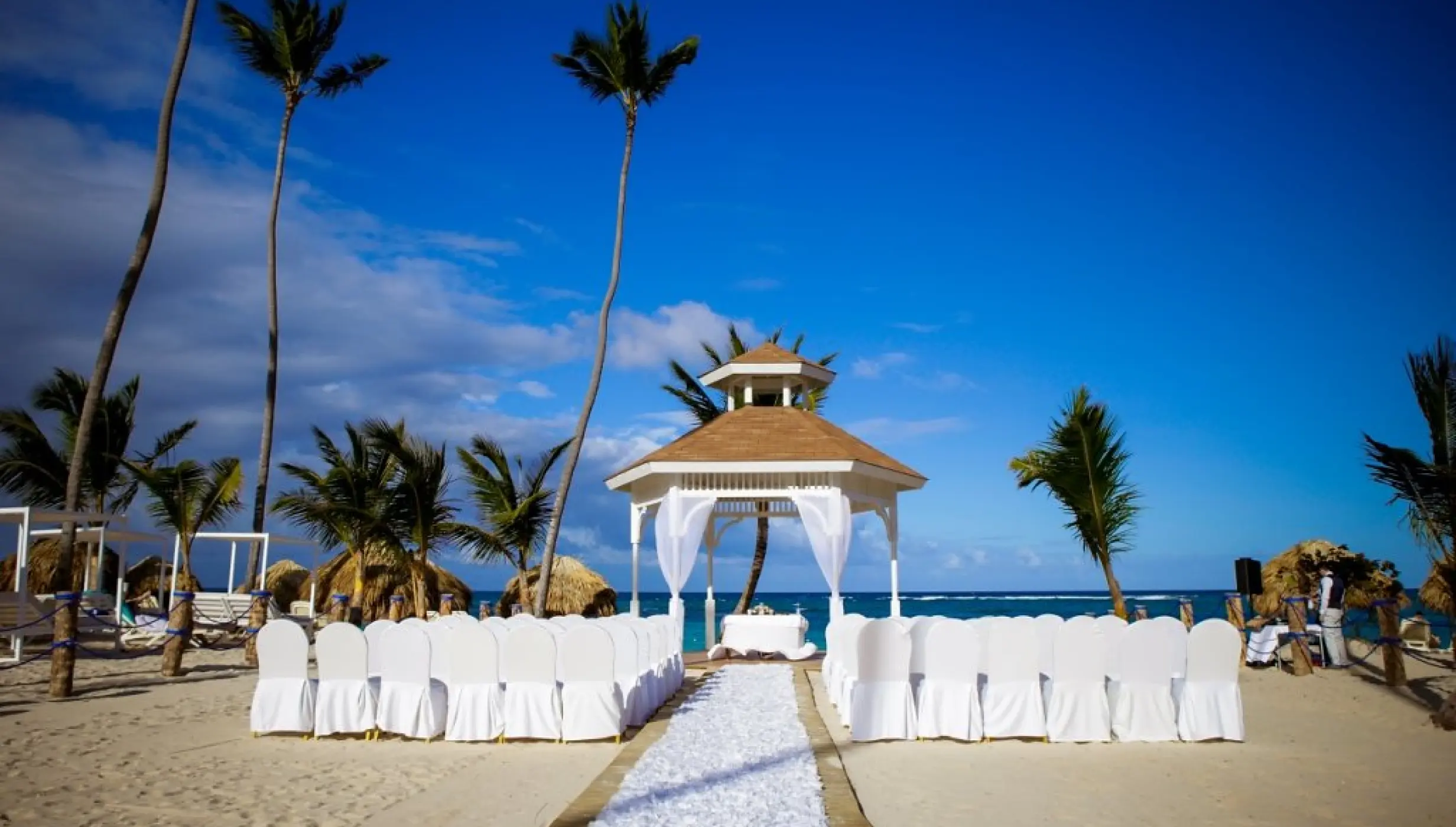 Beachfront wedding ceremony gazebo with white chairs and floral aisle at Majestic Mirage, Punta Cana