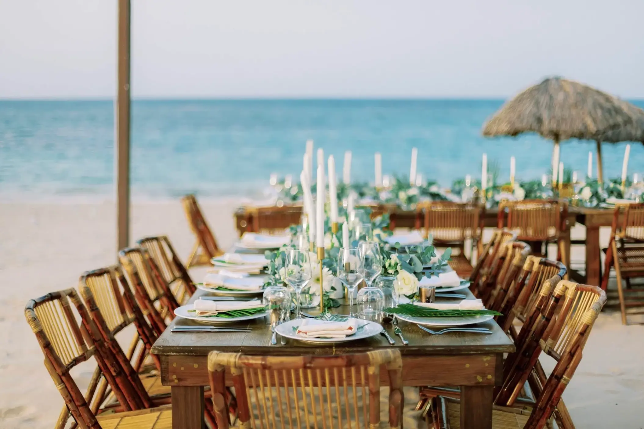 Beachfront wedding reception setup with wooden tables and bamboo chairs at Majestic Mirage, Punta Cana