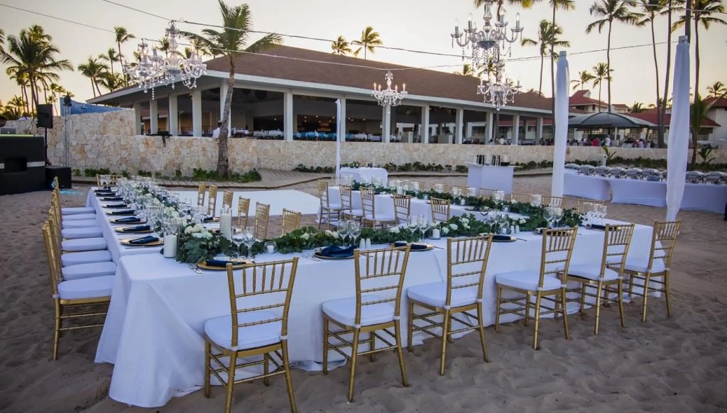 Beach wedding reception with gold chairs and crystal chandeliers at Majestic Mirage, Punta Cana
