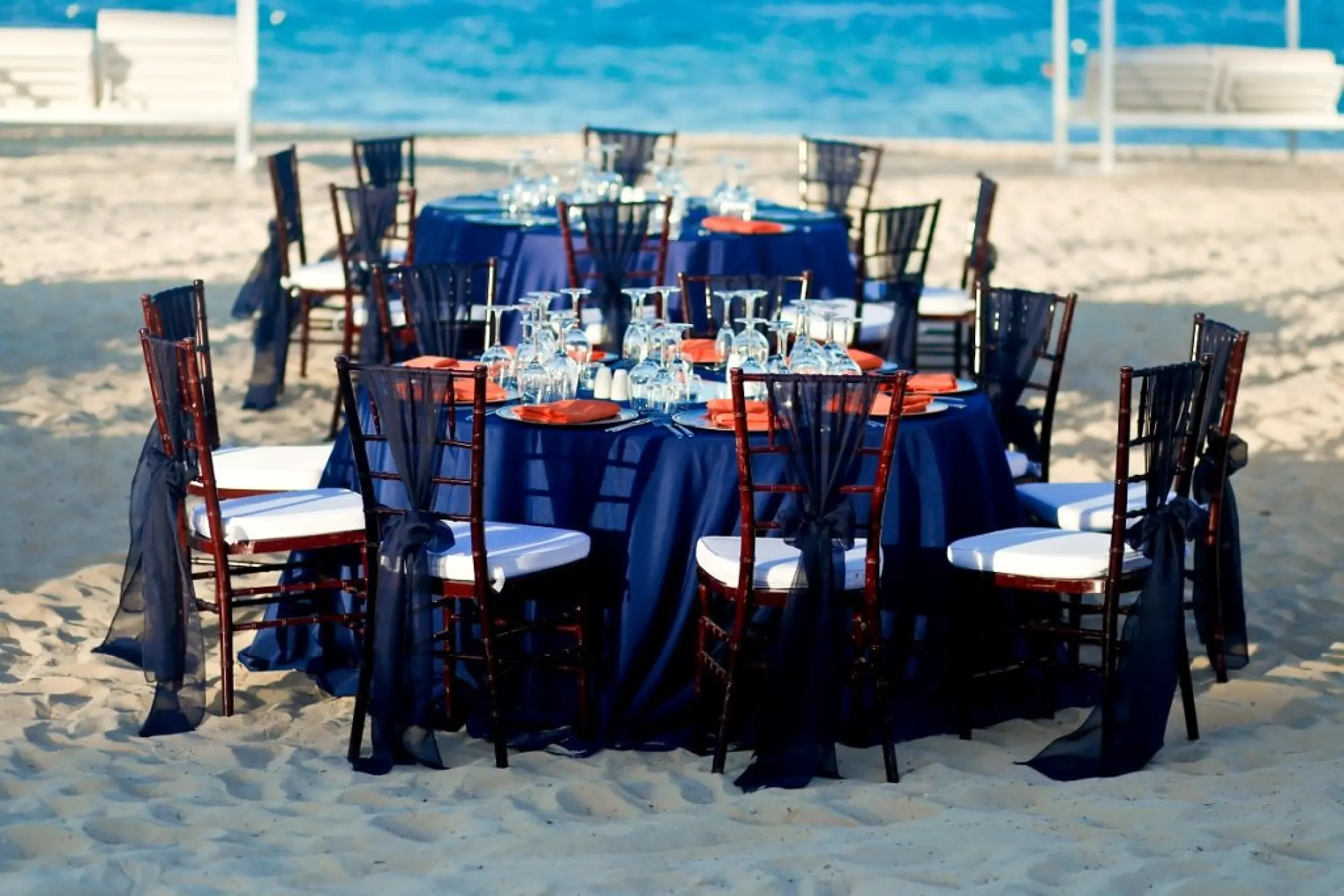 Beachfront wedding reception with navy linens and orange napkins at Majestic Mirage, Punta Cana