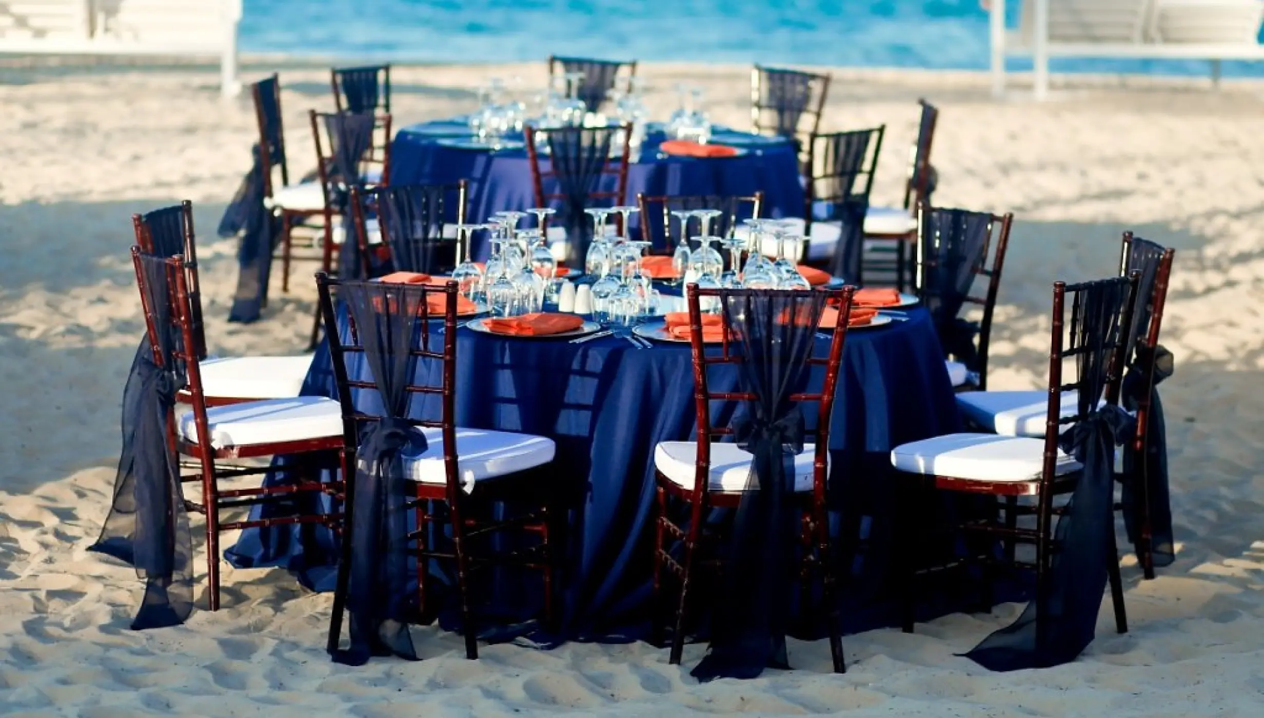 Beachfront wedding reception with navy linens and orange napkins at Majestic Mirage, Punta Cana