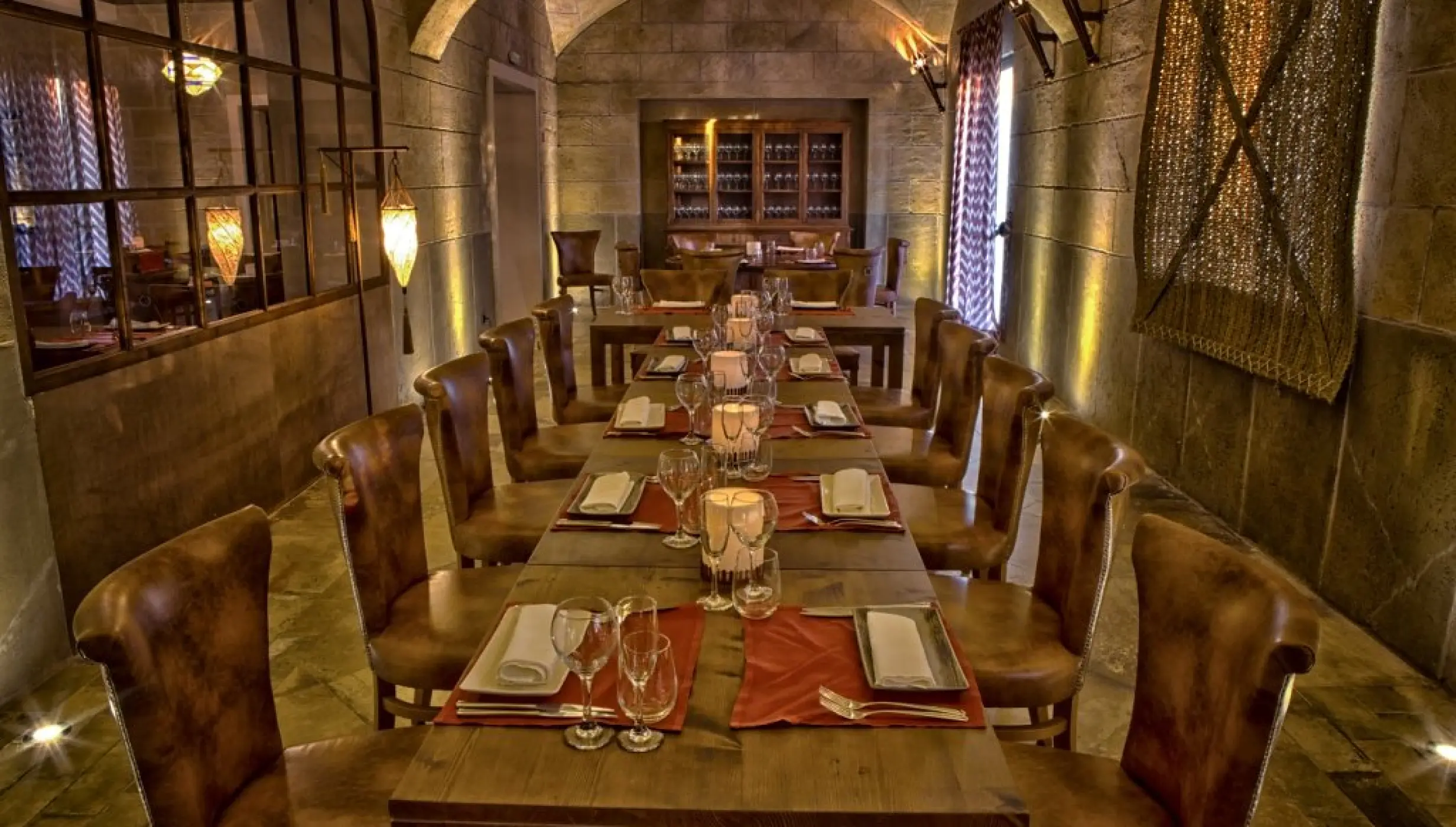 Don Jaume restaurant with a long wooden dining table and stone walls at Majestic Mirage, Punta Cana