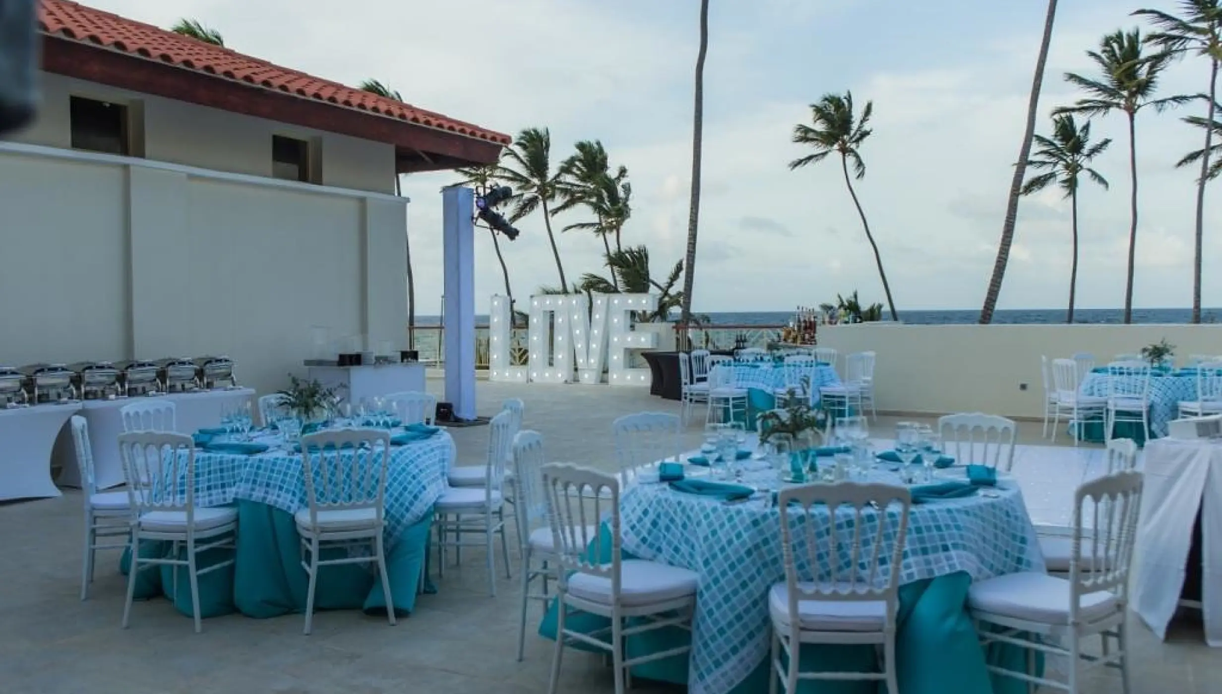 Private terrace wedding reception with teal décor and marquee LOVE sign at Majestic Mirage, Punta Cana