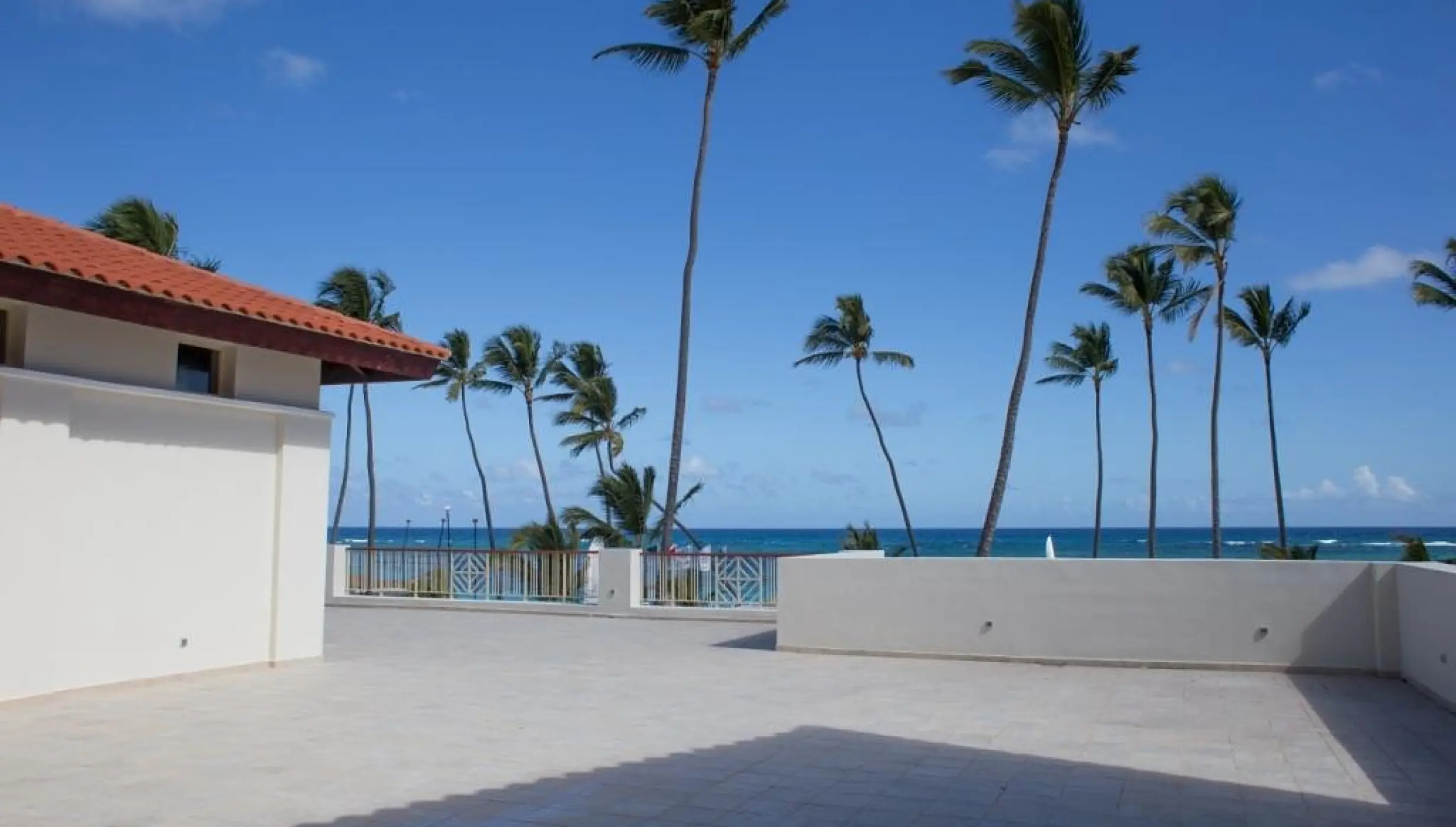 Private stone terrace overlooking palm trees and the ocean at Majestic Mirage Punta Cana