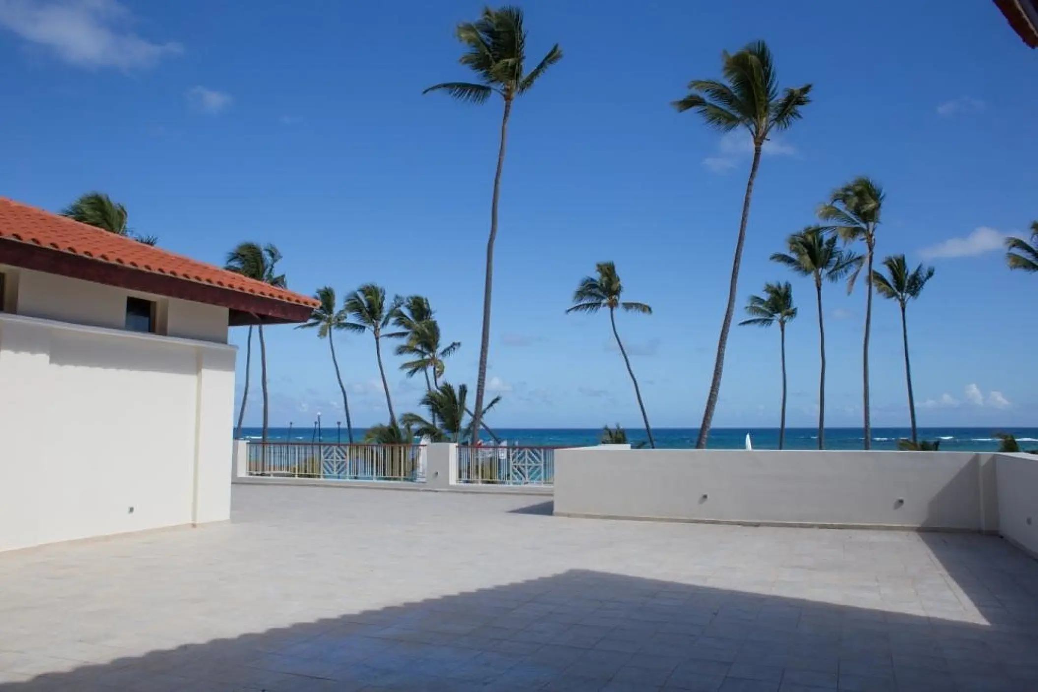 Private stone terrace overlooking palm trees and the ocean at Majestic Mirage Punta Cana