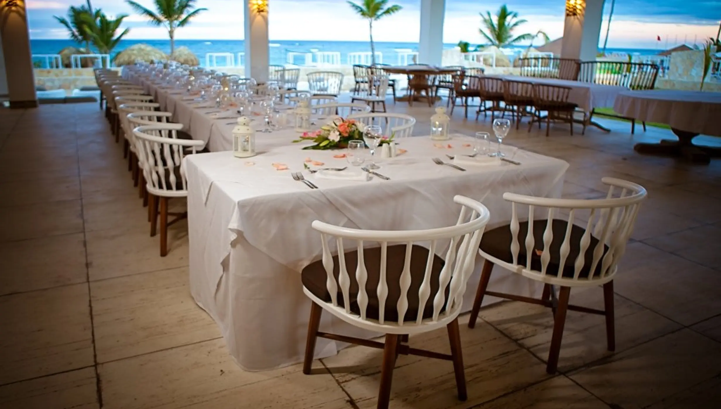 Covered seaside wedding reception venue with white tables and chairs at Majestic Mirage, Punta Cana