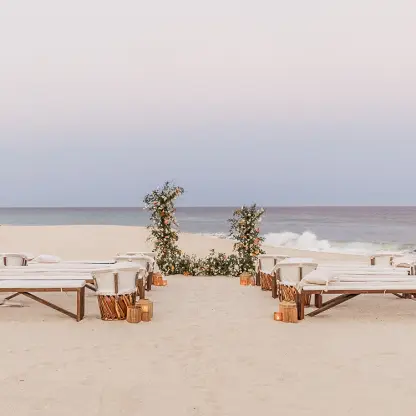 Beachfront wedding ceremony with wooden benches and floral arch at Mar Del Cabo, Cabo San Lucas