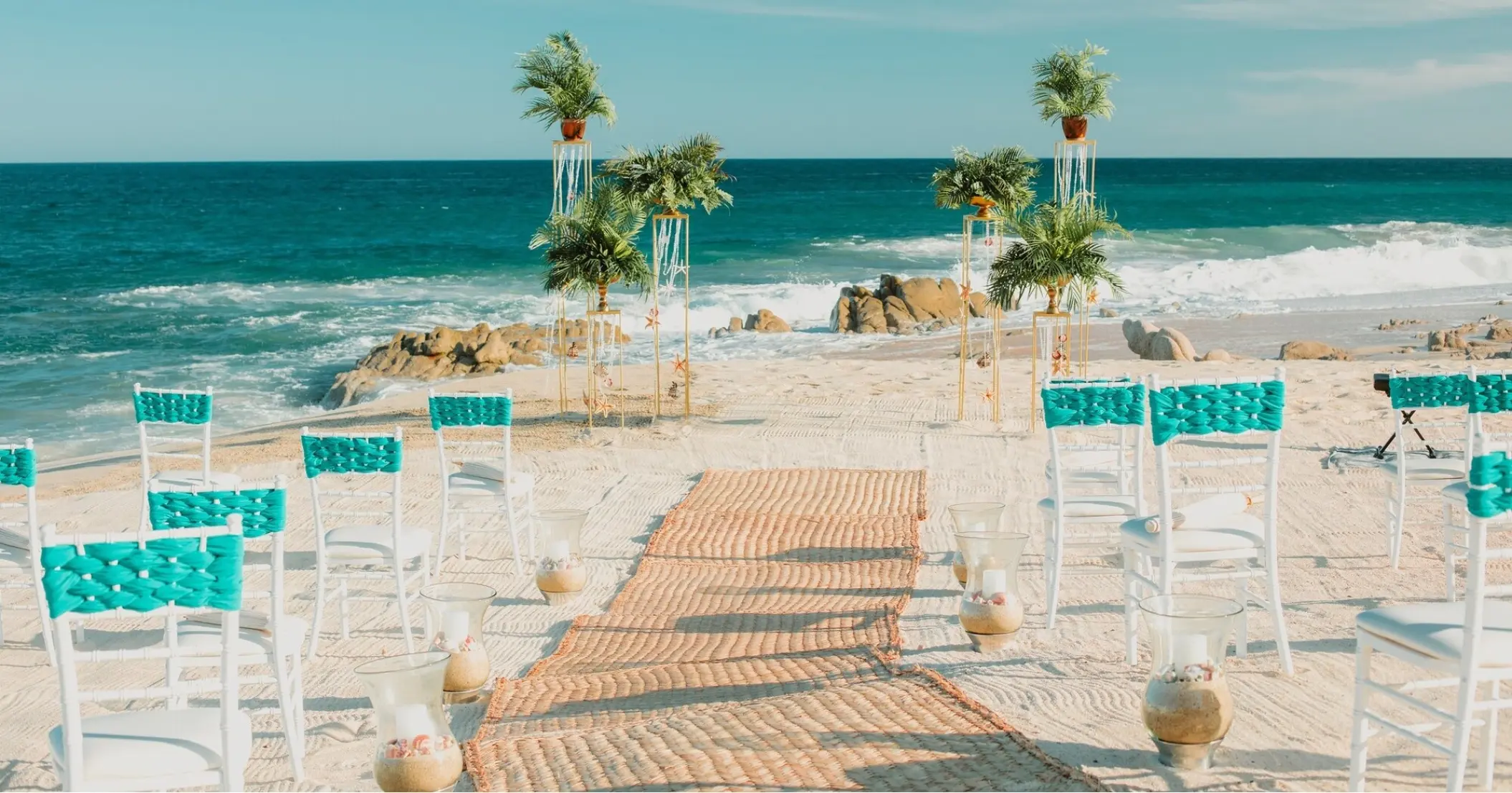Beachfront wedding ceremony with turquoise chairs and woven aisle runner at Mar Del Cabo, Cabo San Lucas