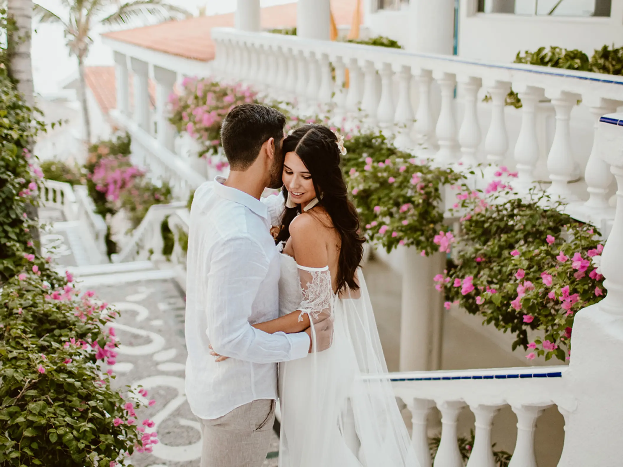The couple embracing on a floral balcony at Mar Del Cabo, Cabo San Lucas