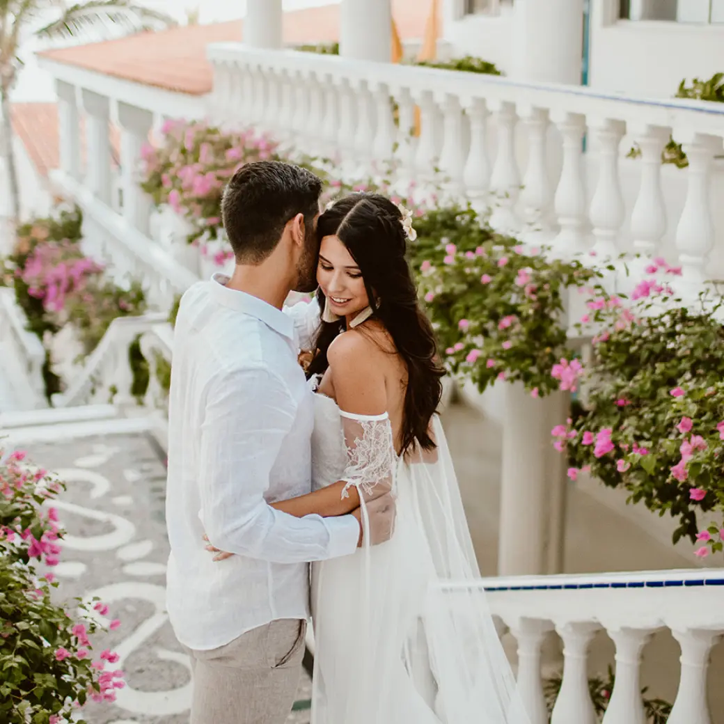 The couple embracing on a floral balcony at Mar Del Cabo, Cabo San Lucas