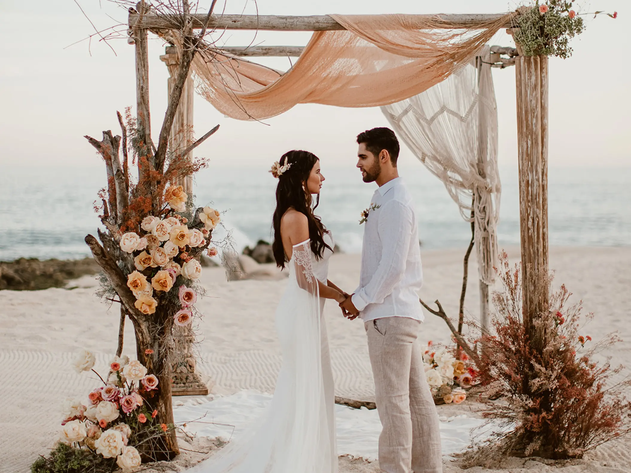 Beachfront wedding ceremony under a wooden arch at Mar Del Cabo, Cabo San Lucas