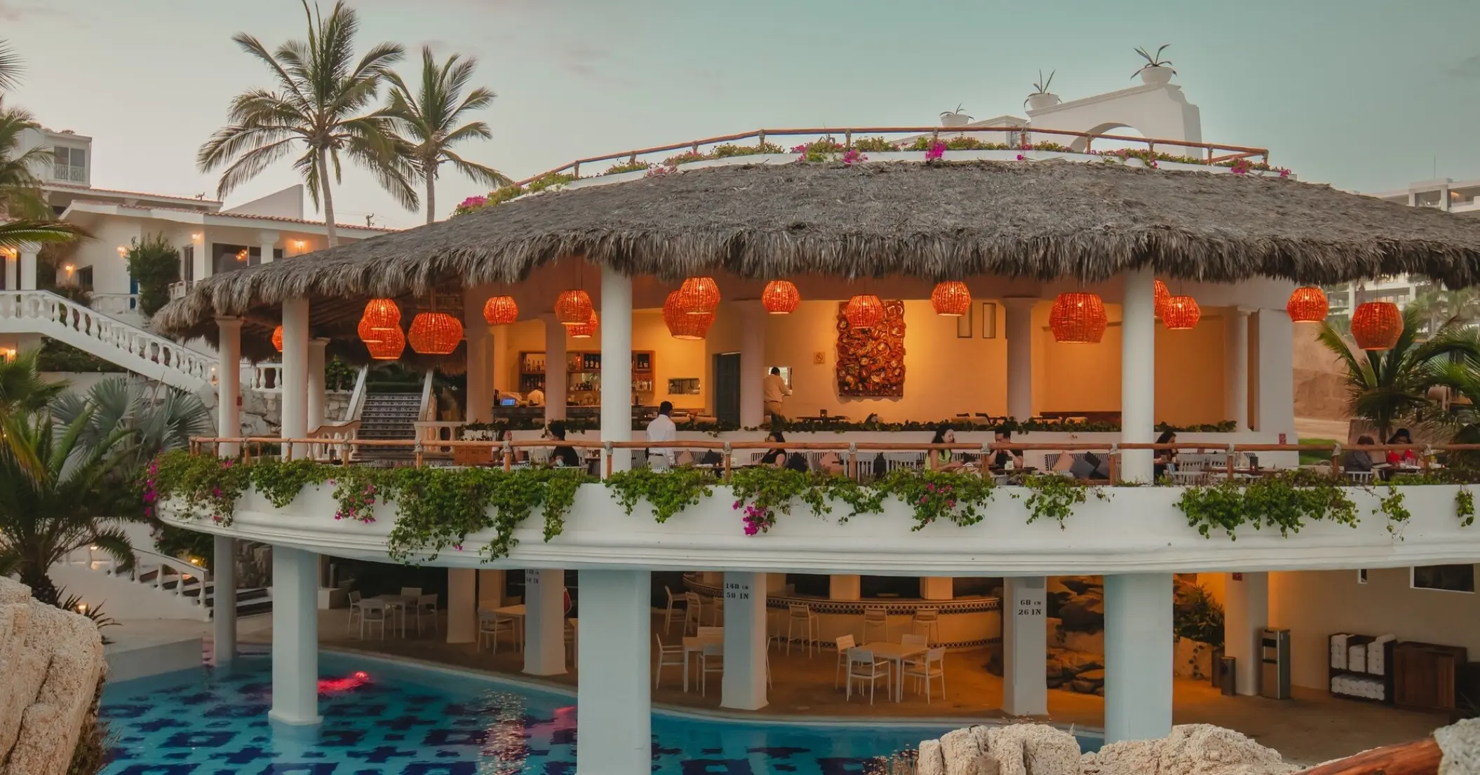 Encanto Restaurant with orange lanterns and a thatched roof at Mar Del Cabo, Cabo San Lucas