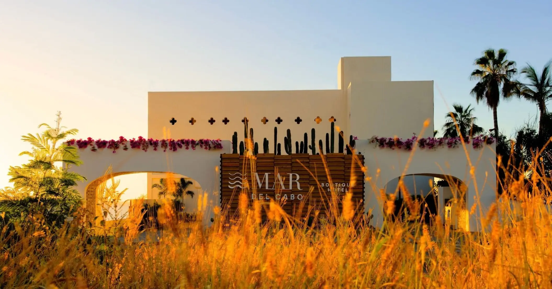 Mar Del Cabo entrance facade with white arches and bougainvillea flowers, Cabo San Lucas