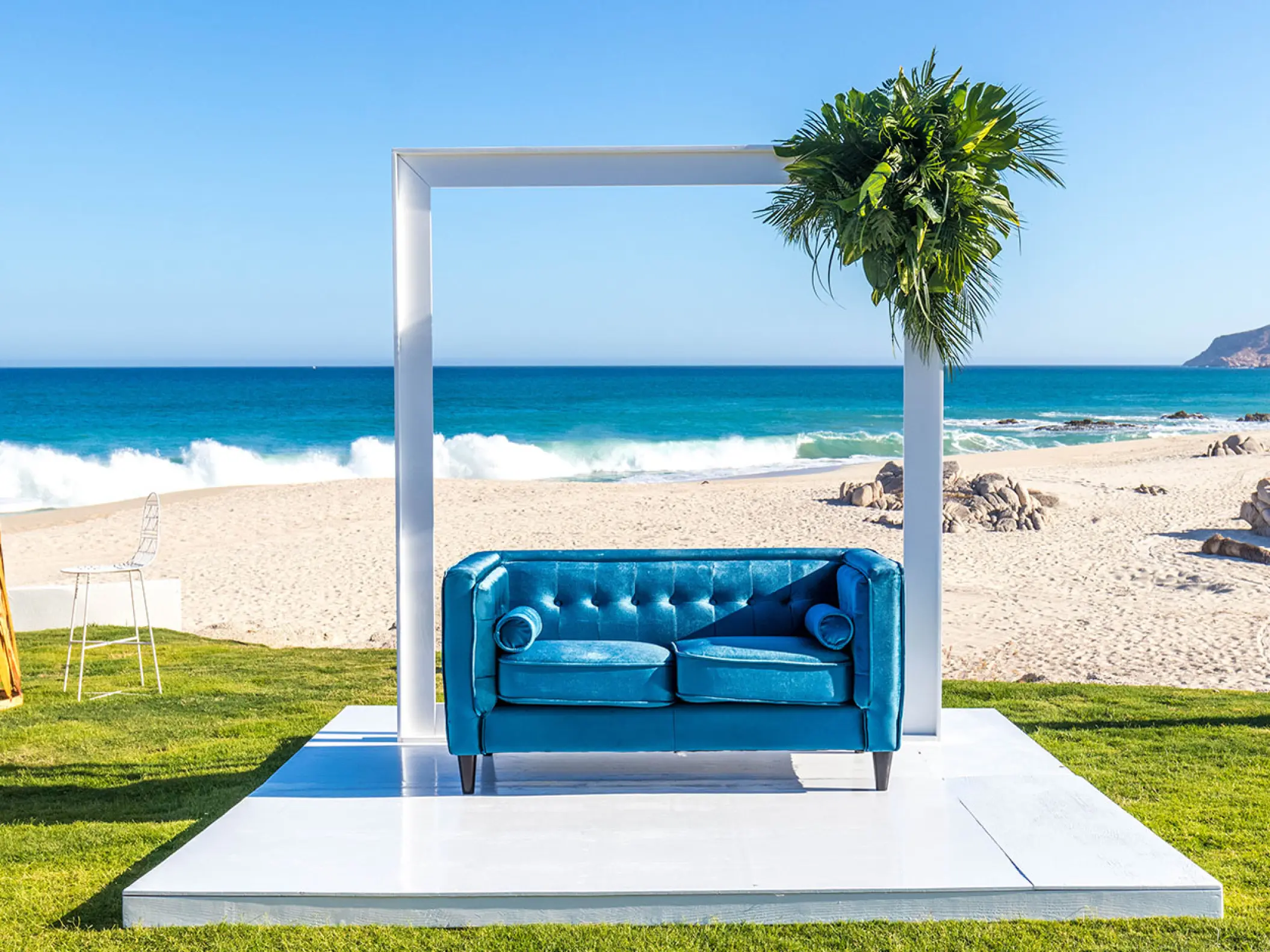 Blue velvet sofa under a white wedding arch at Mar Del Cabo, Cabo San Lucas