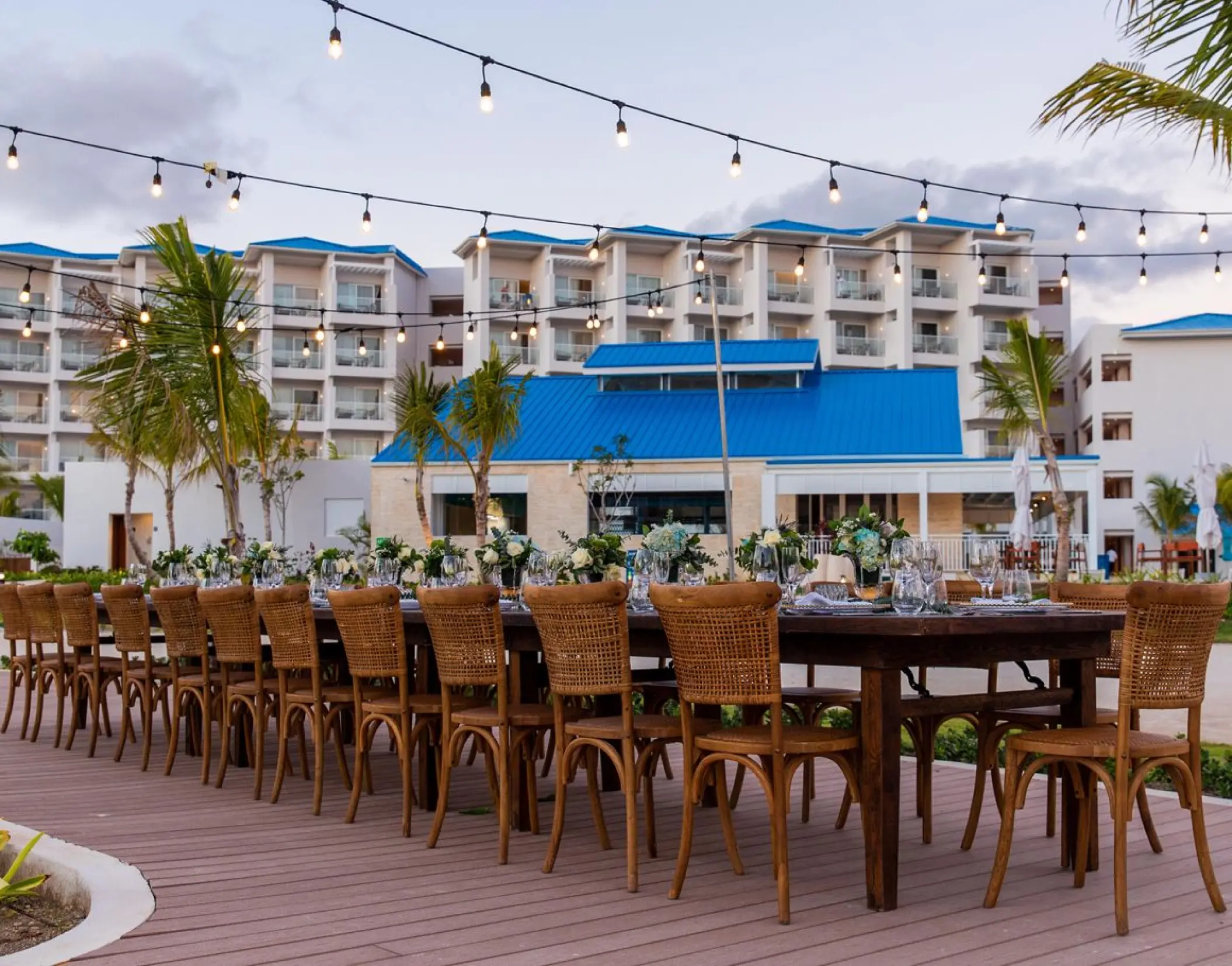 Outdoor wedding reception setup with long wooden tables and string lights at Margaritaville Cap Cana, Punta Cana