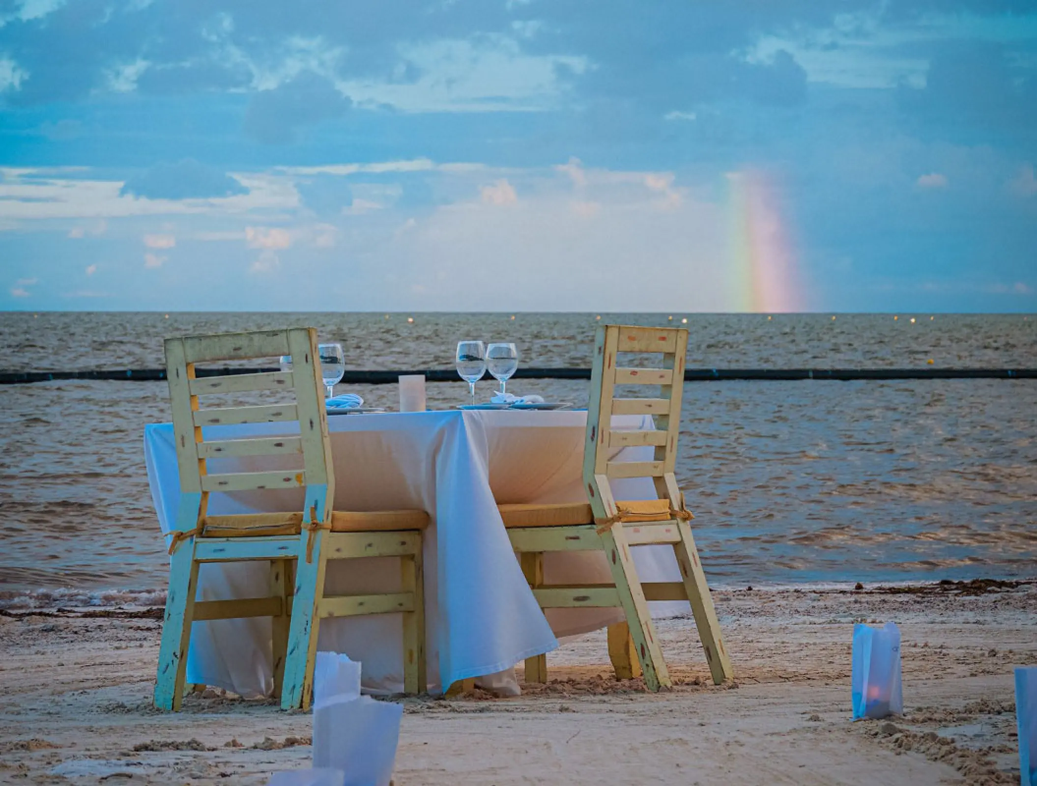 Private beach dinner setup with a rainbow on the horizon at Margaritaville Island Reserve Riviera Cancun