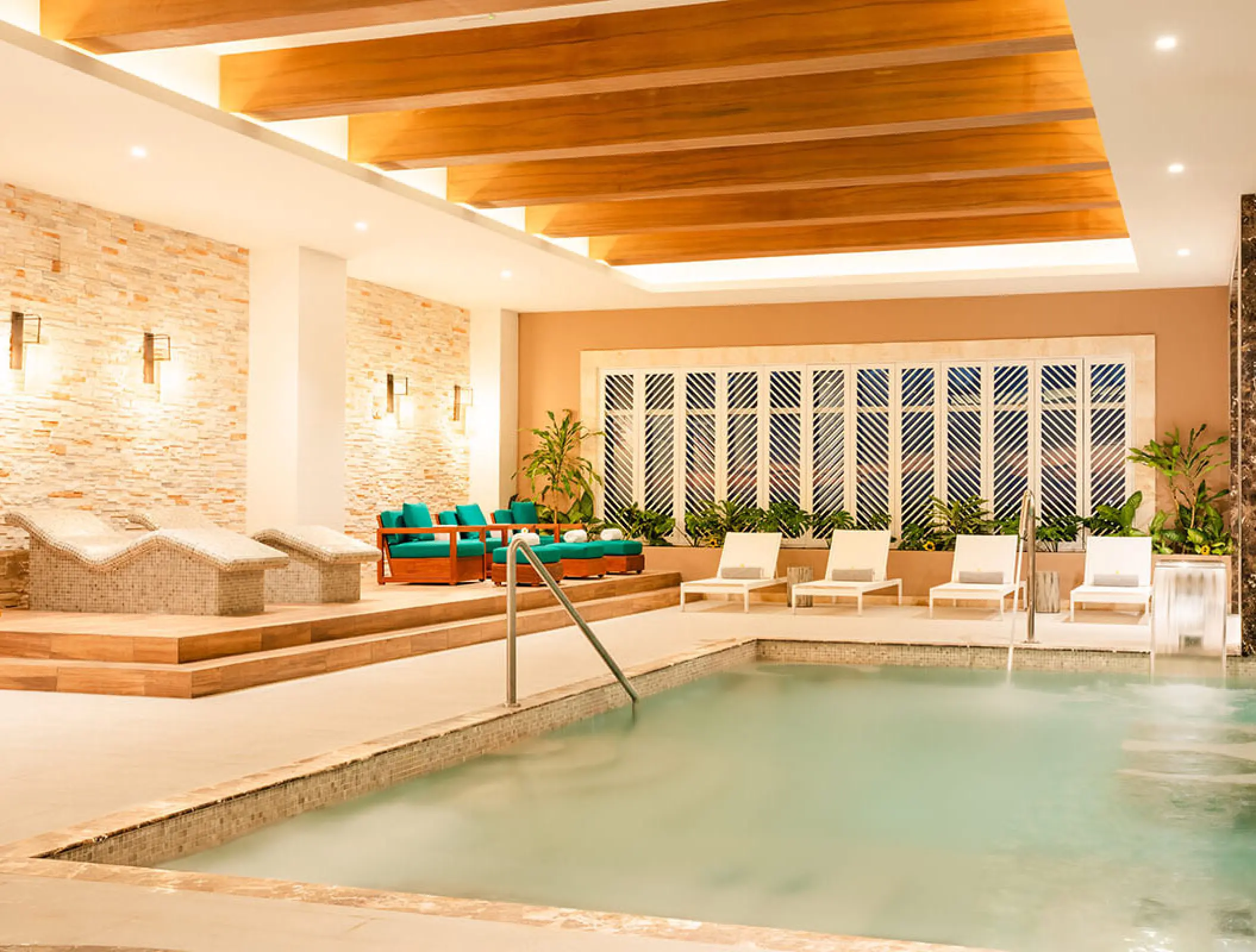 Indoor hydrotherapy pool and stone lounge chairs at Margaritaville Island Reserve Riviera Maya