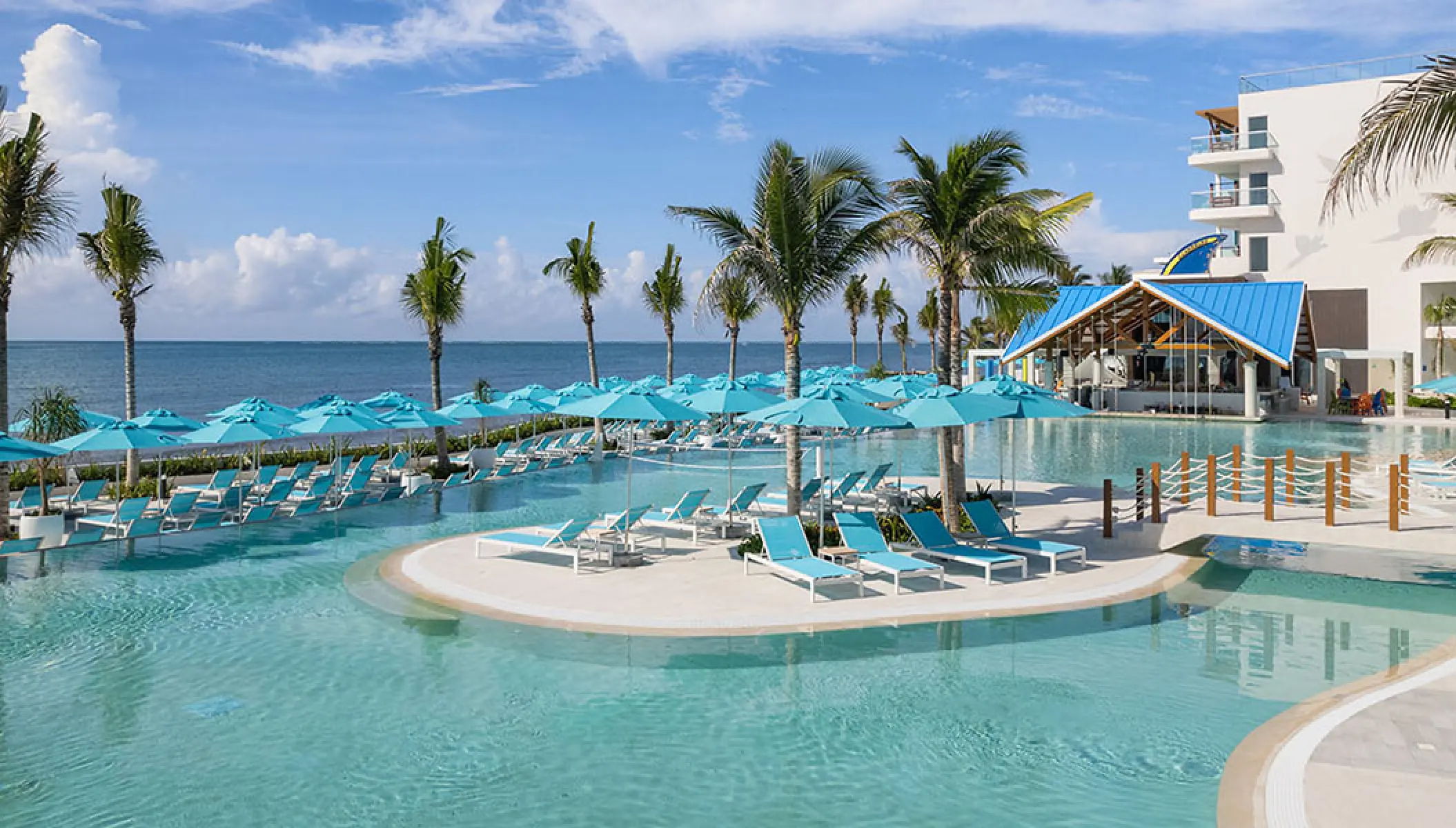 Main pool area with blue umbrellas and palm trees at Margaritaville Island Reserve Riviera Maya