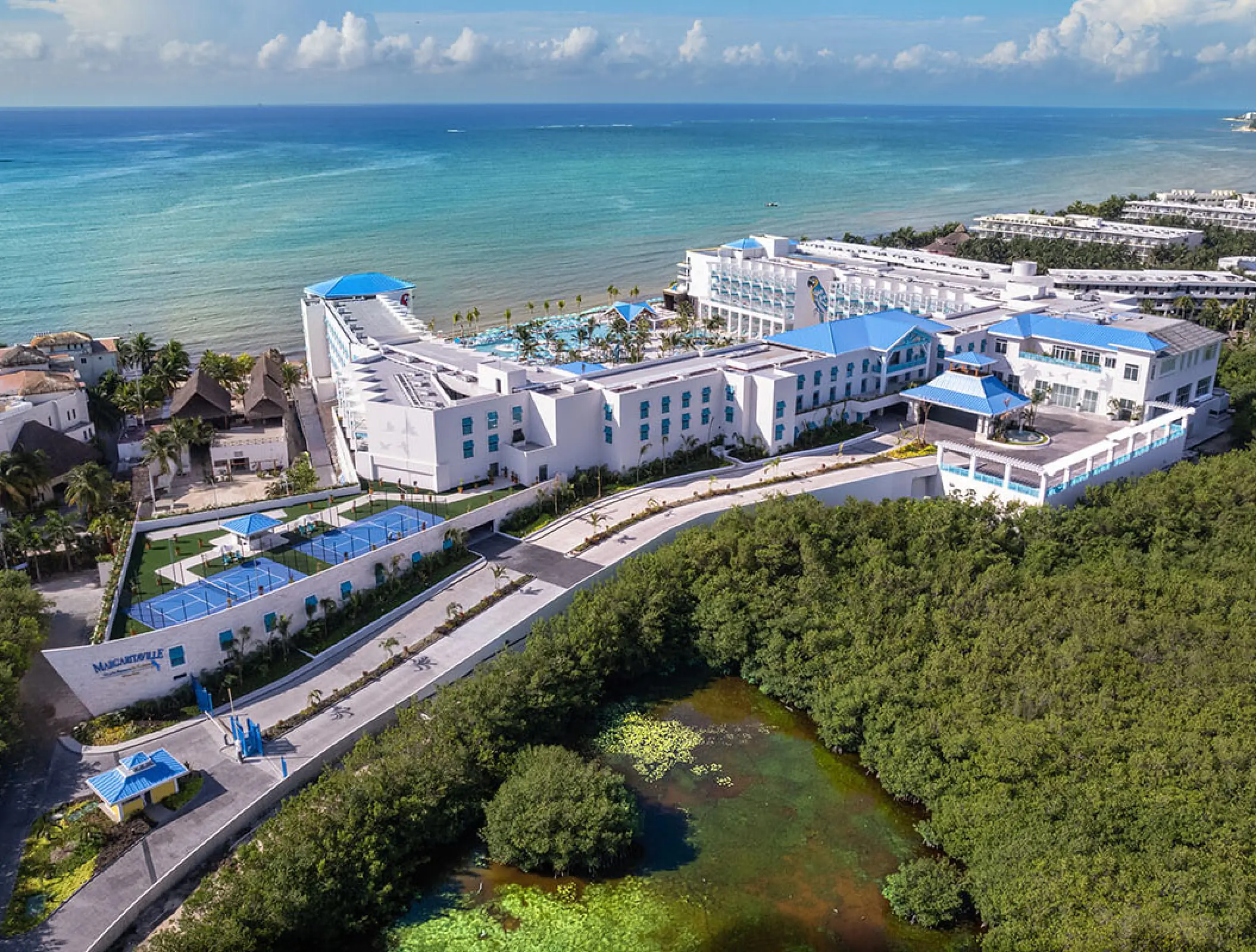 Aerial view of Margaritaville Island Reserve Riviera Maya buildings and pools along the Caribbean coastline