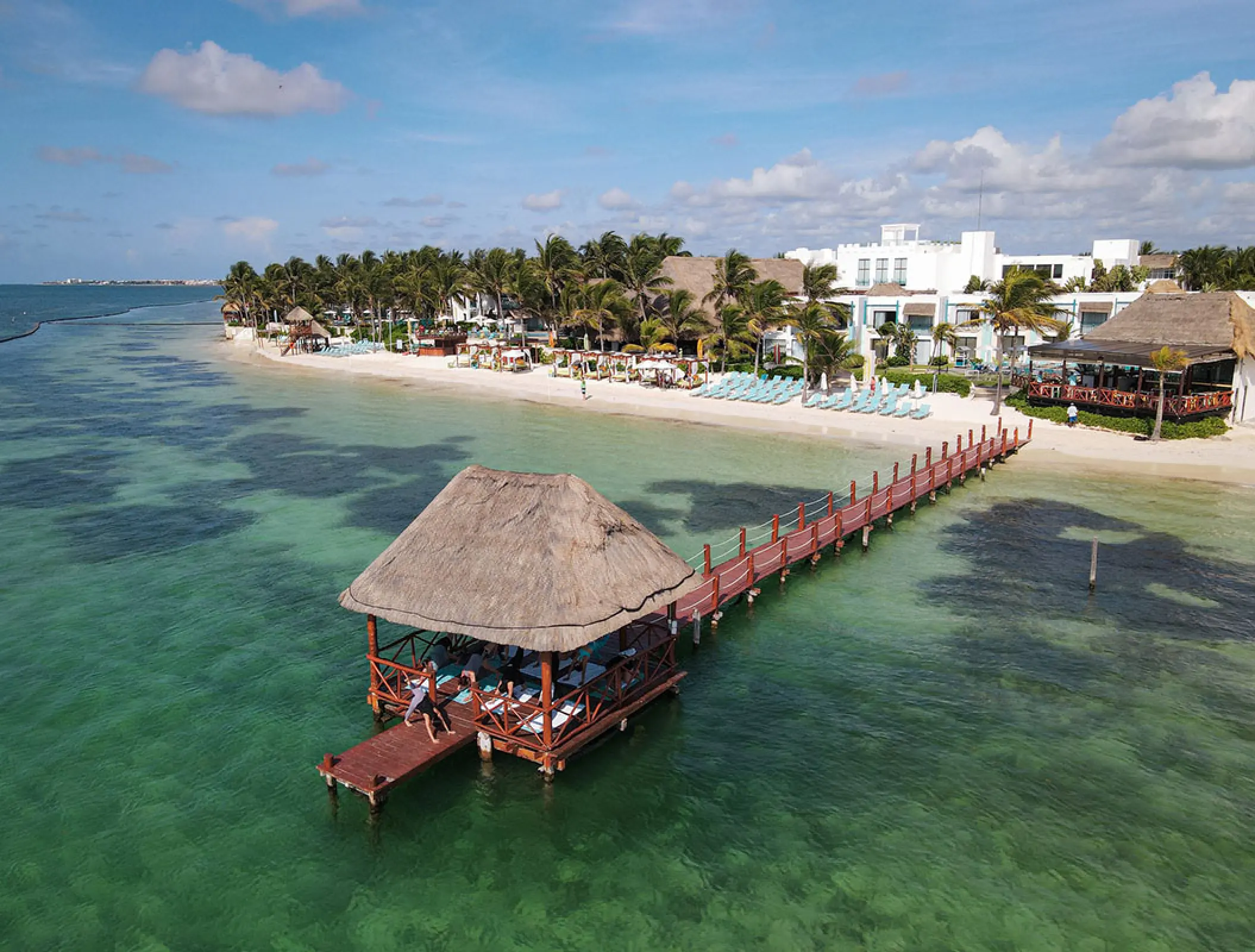 Aerial view of the beachfront and overwater pier palapa at Margaritaville Riviera Cancun