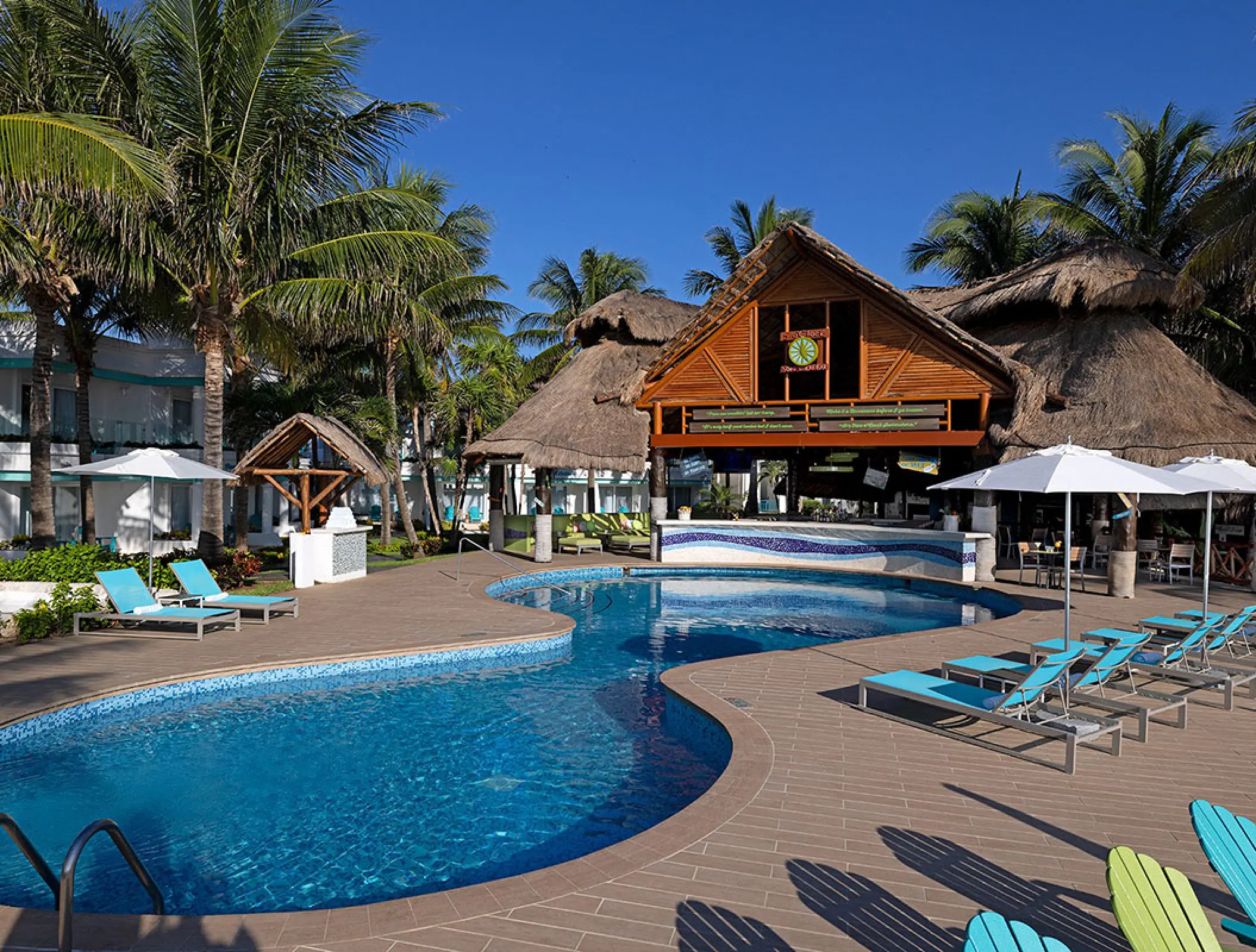 Margaritaville Island Reserve Riviera Cancun pool area and thatched-roof bar surrounded by palm trees, Cancun