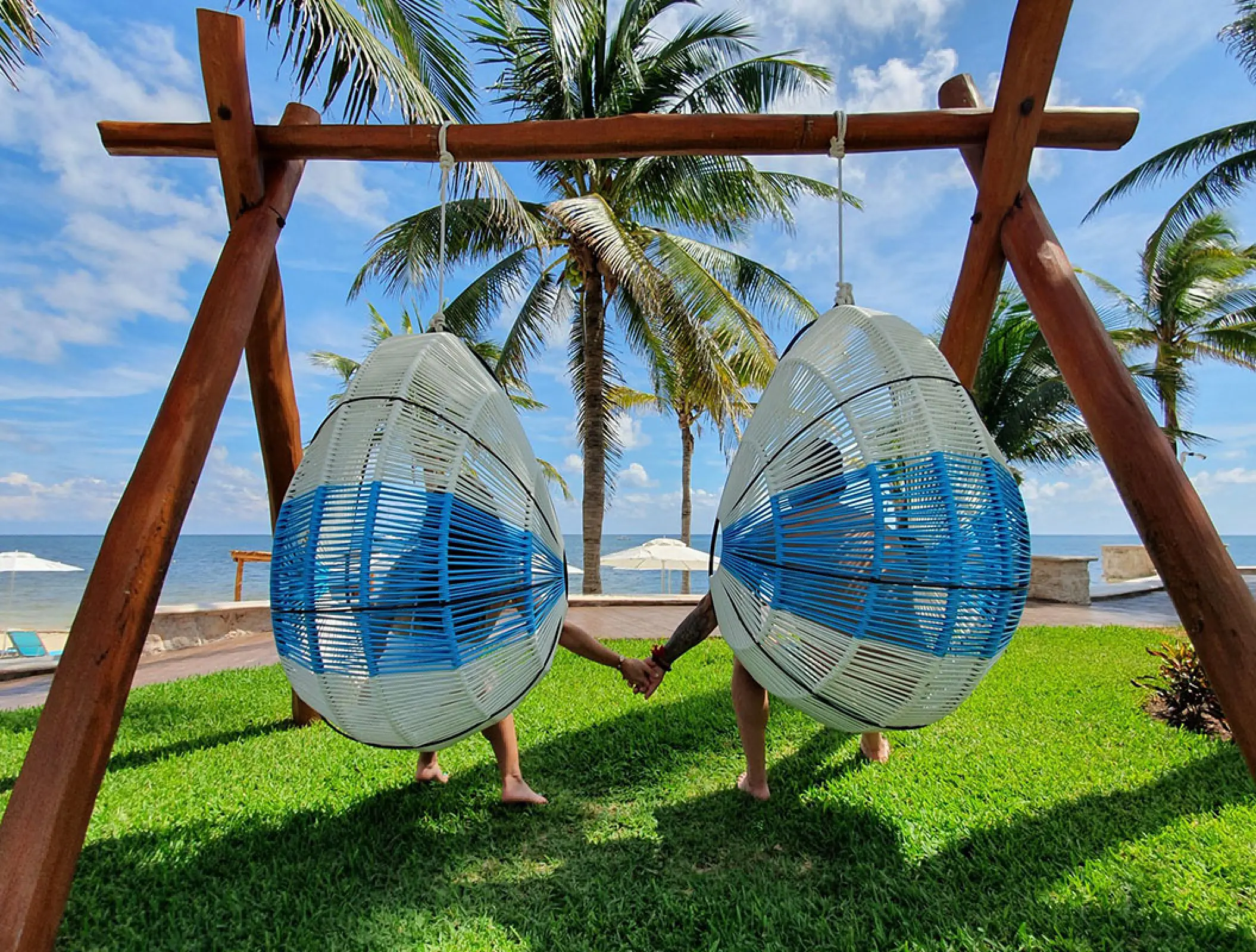 Couple holding hands while sitting in hanging chairs at Margaritaville Island Reserve Riviera Cancun