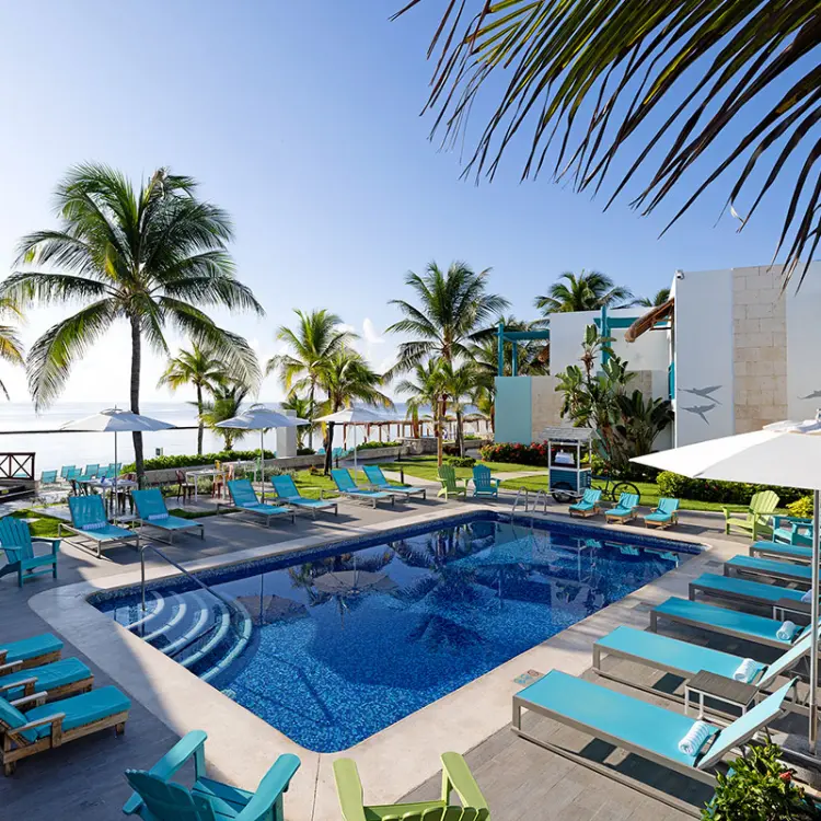 Margaritaville Island Reserve Riviera Cancun outdoor pool area with turquoise lounge chairs and palm trees, Cancun