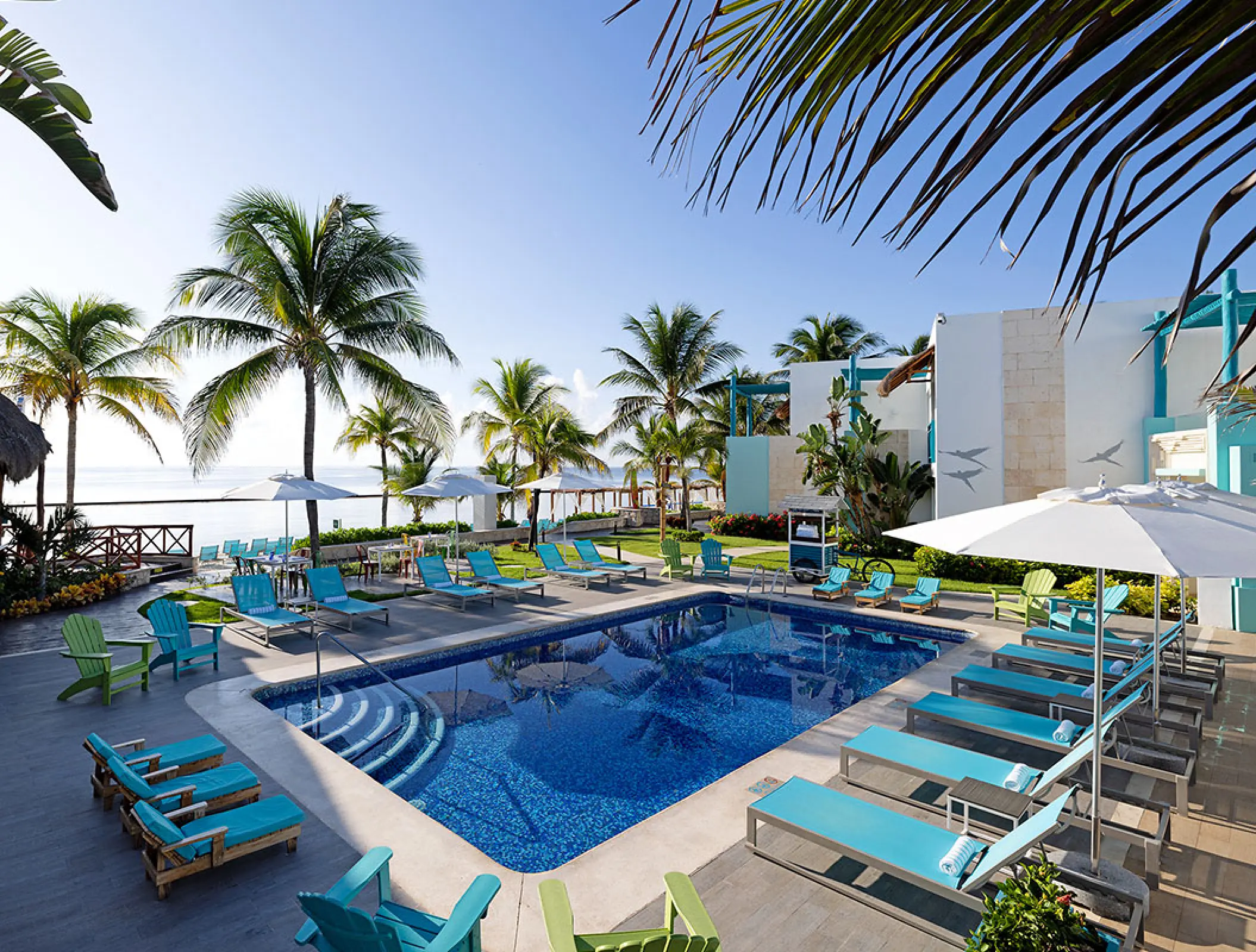 Margaritaville Island Reserve Riviera Cancun outdoor pool area with turquoise lounge chairs and palm trees, Cancun