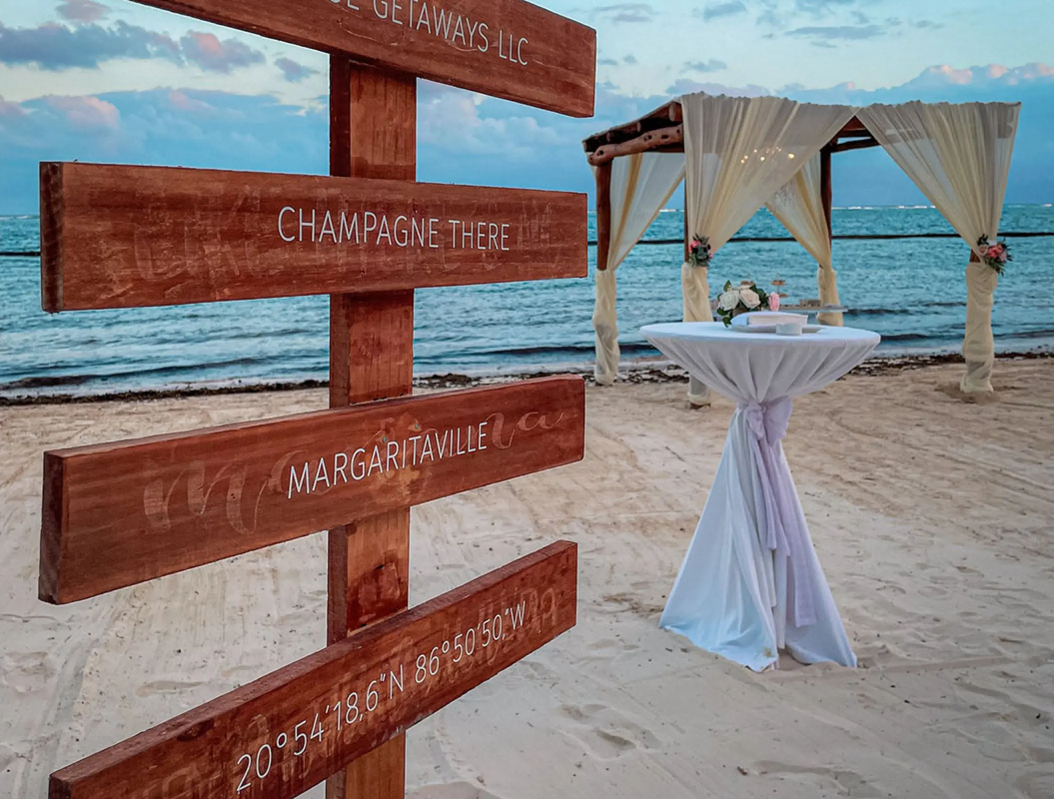 Wooden direction sign and beach wedding ceremony setup at Margaritaville Island Reserve Riviera Cancun, Cancun