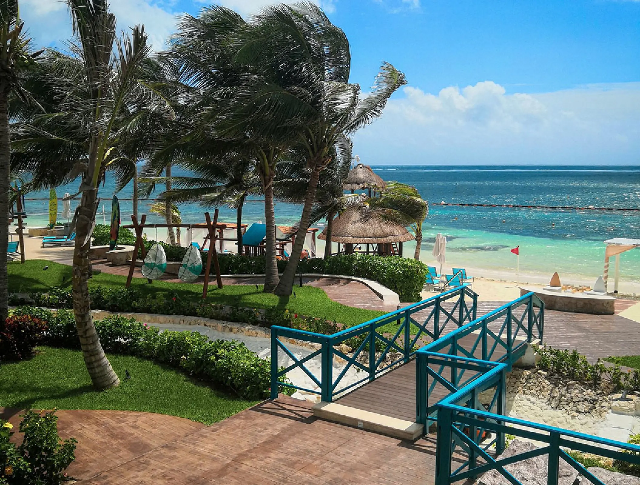Turquoise footbridge and palm trees overlooking the beach at Margaritaville Island Reserve Riviera Cancun