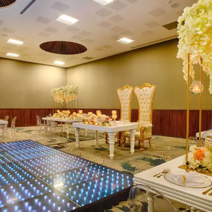 Indoor ballroom wedding reception with a lit dance floor and white floral decor at Armony Marival, Puerto Vallarta