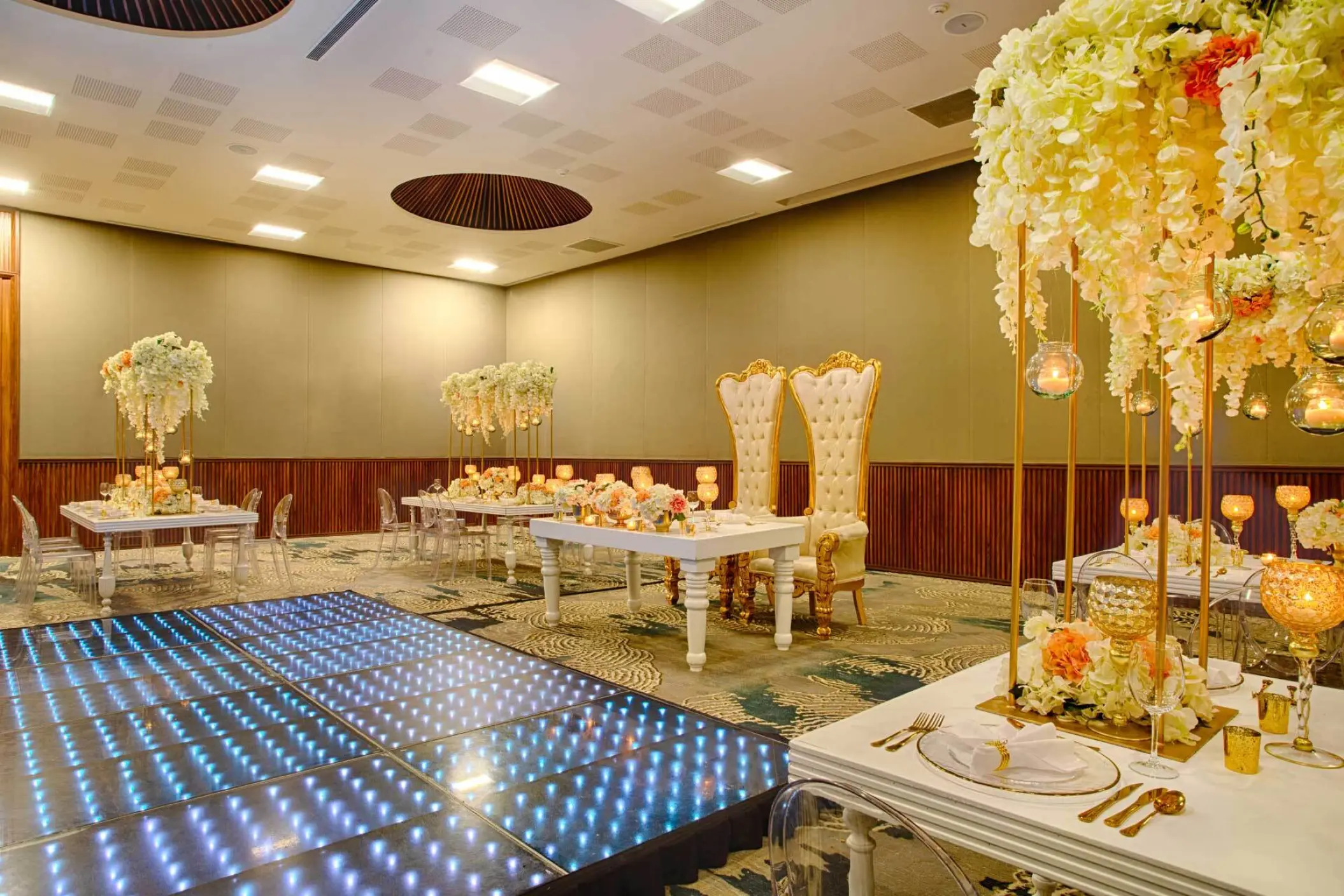 Indoor ballroom wedding reception with a lit dance floor and white floral decor at Armony Marival, Puerto Vallarta