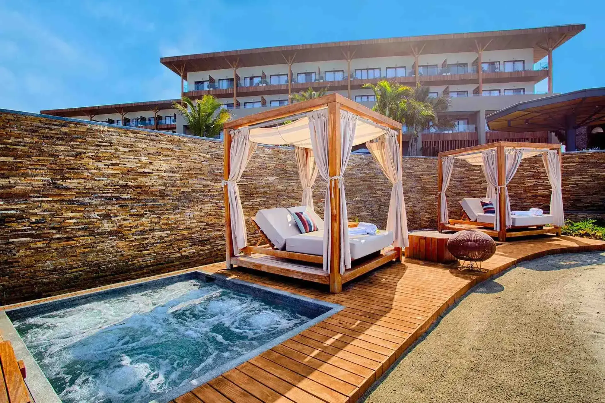 Private hot tub and poolside cabanas on a wooden deck at Marival Armony, Puerto Vallarta