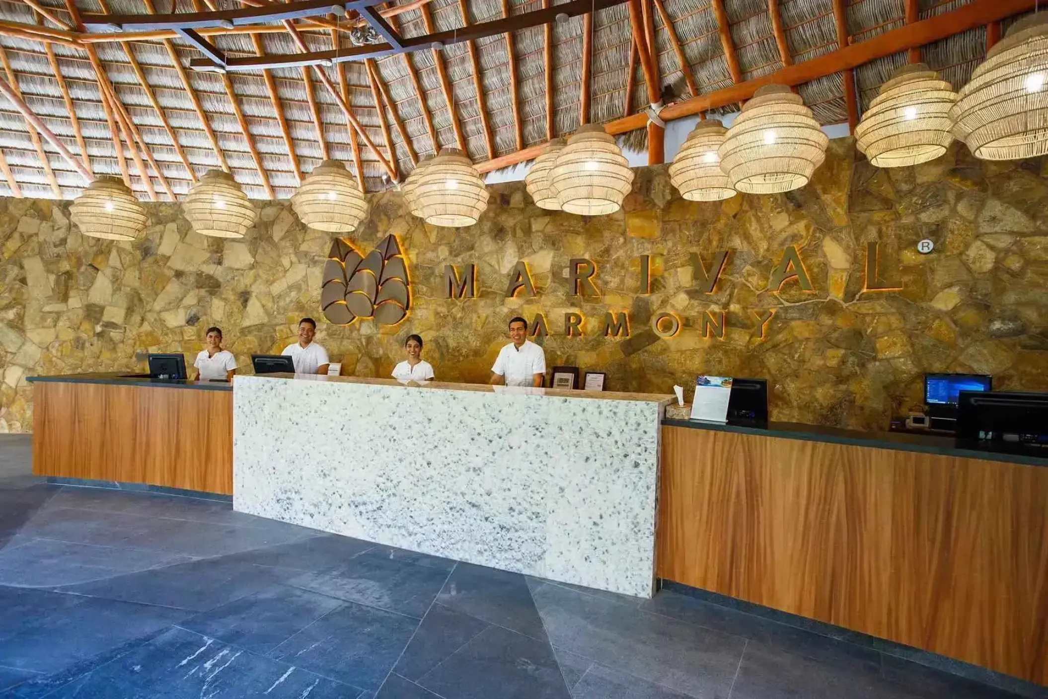 Stone lobby reception desk with woven pendant lights at Marival Armony, Puerto Vallarta