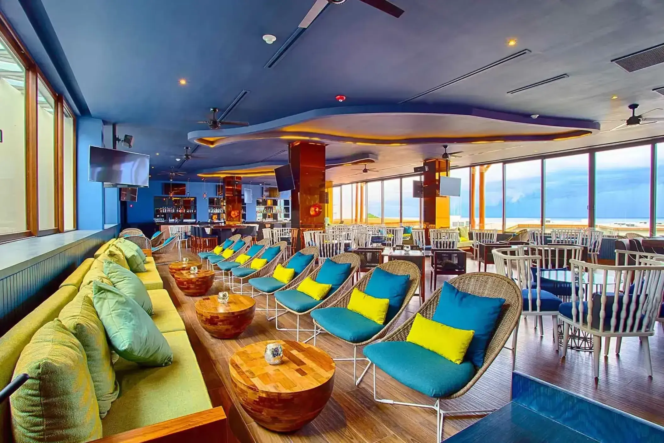 Indoor lounge and bar area with turquoise chairs at Armony Marival, Puerto Vallarta